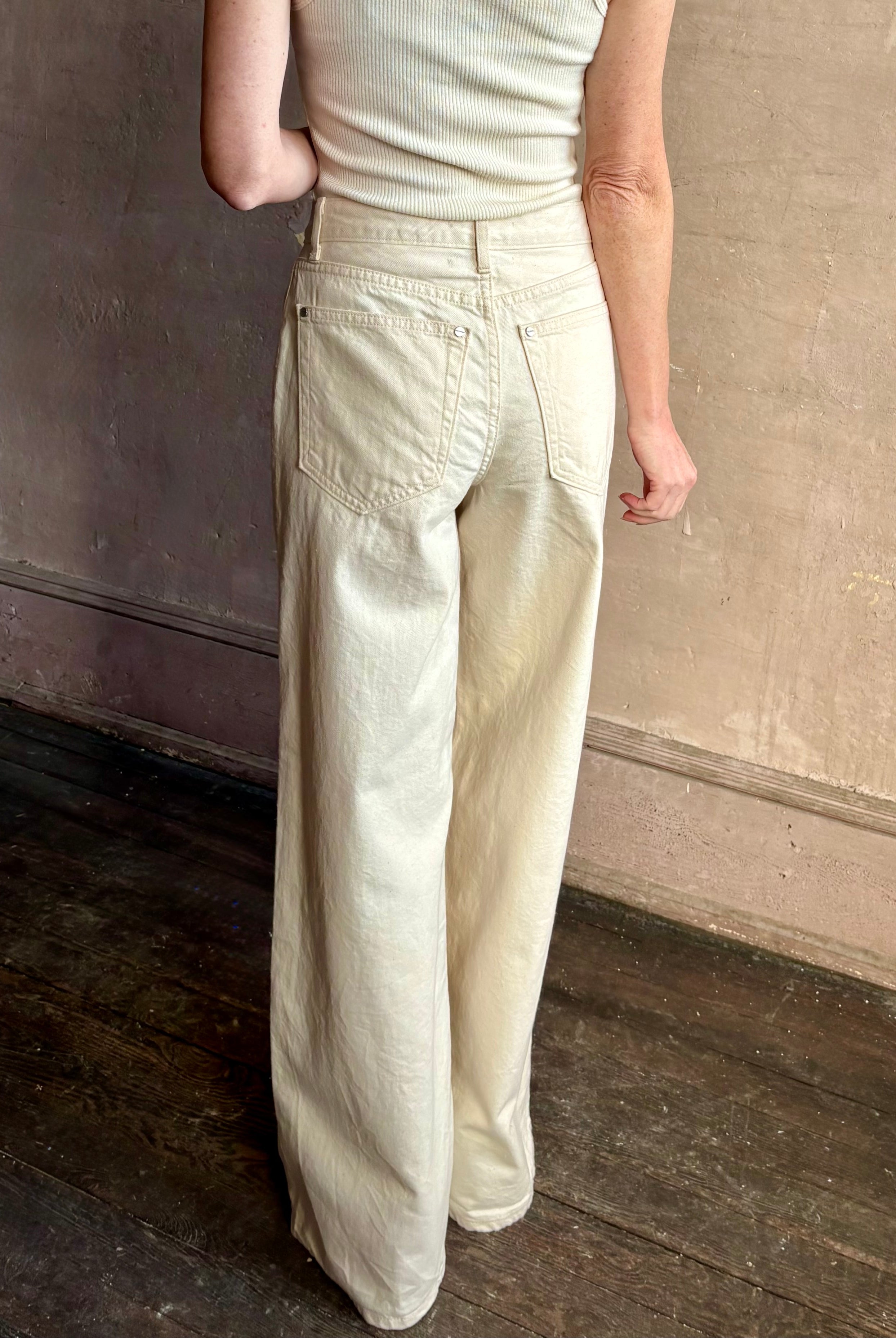 Mature woman wearing premium cotton TWP Tiny Dancer rigid denim with relaxed high rise and wide leg in Natural