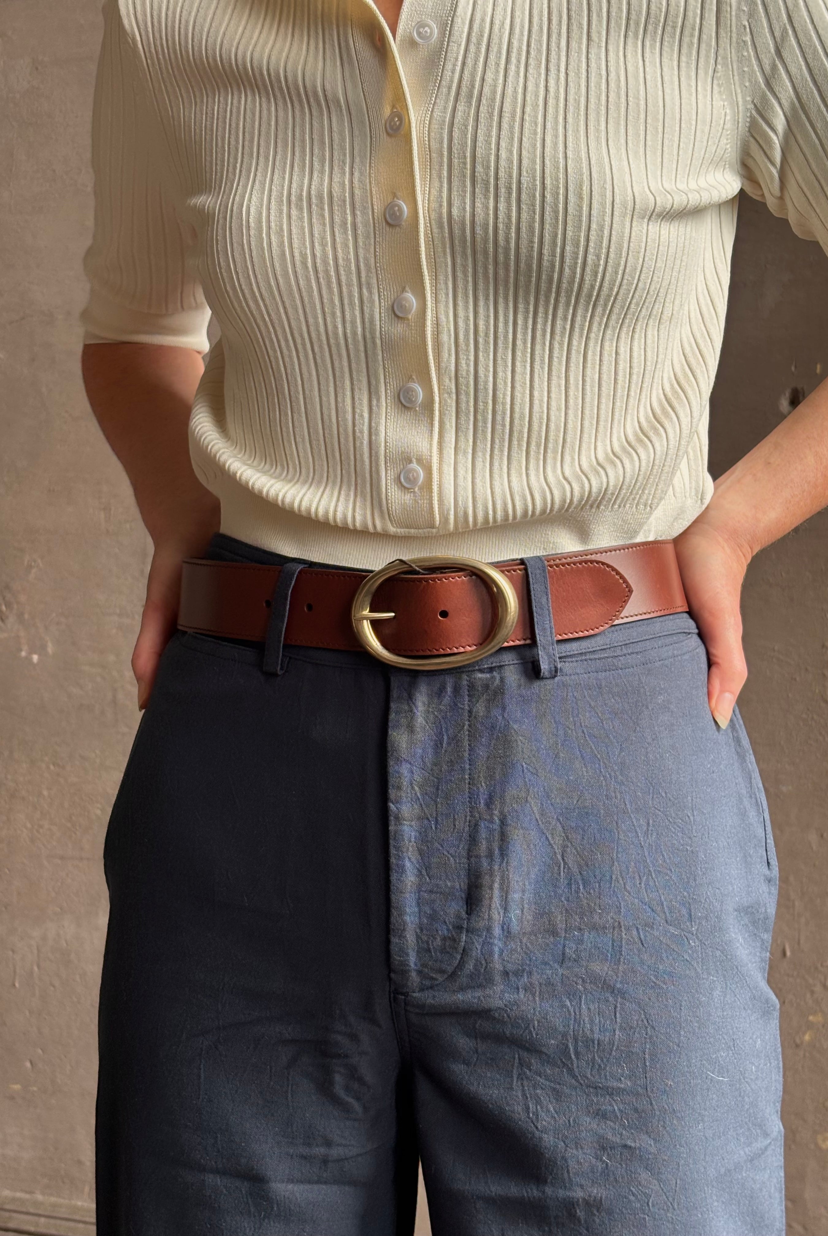 Mature woman wearing a TWP bourbon brown wide leather belt with warm gold tone oval buckle