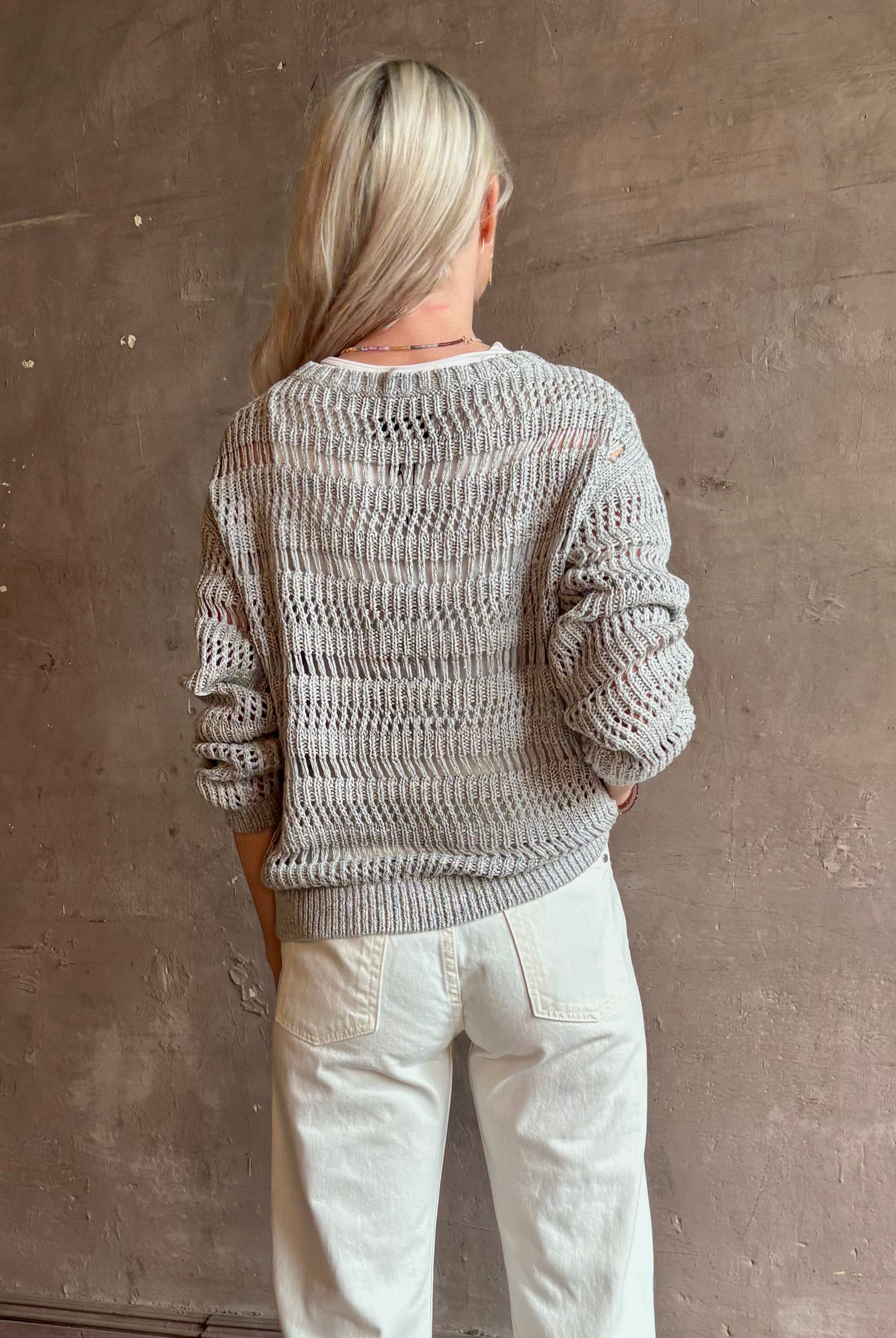 Mature woman wearing Wide Neck Long Sleeve open knit Sweater from TWP in a luxuriously wearable everyday essential rendered in a soft light grey and crafted from an elevated blend of European flax linen and recycled mulberry silk