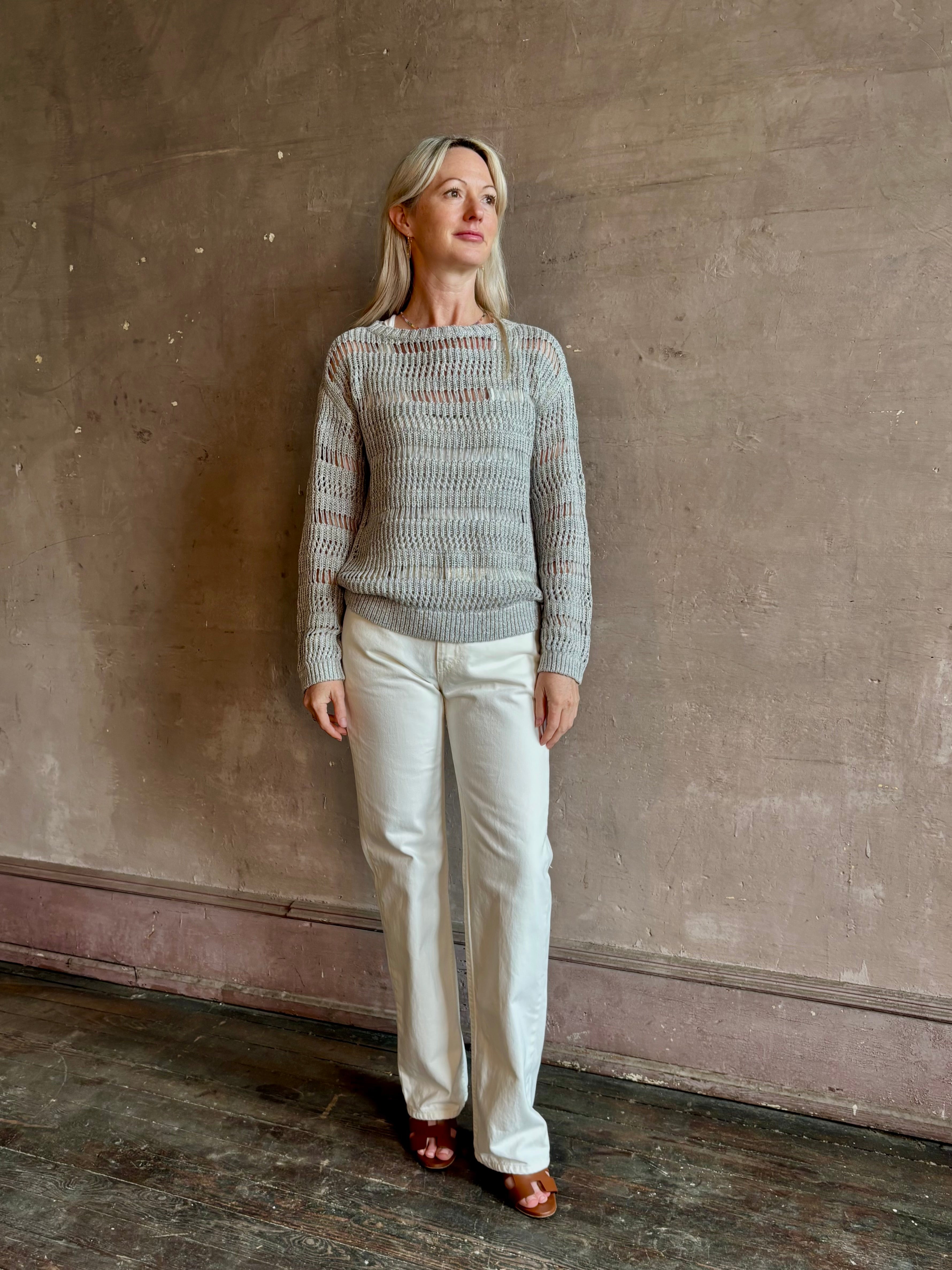Mature woman wearing Wide Neck Long Sleeve open knit Sweater from TWP in a luxuriously wearable everyday essential rendered in a soft light grey and crafted from an elevated blend of European flax linen and recycled mulberry silk