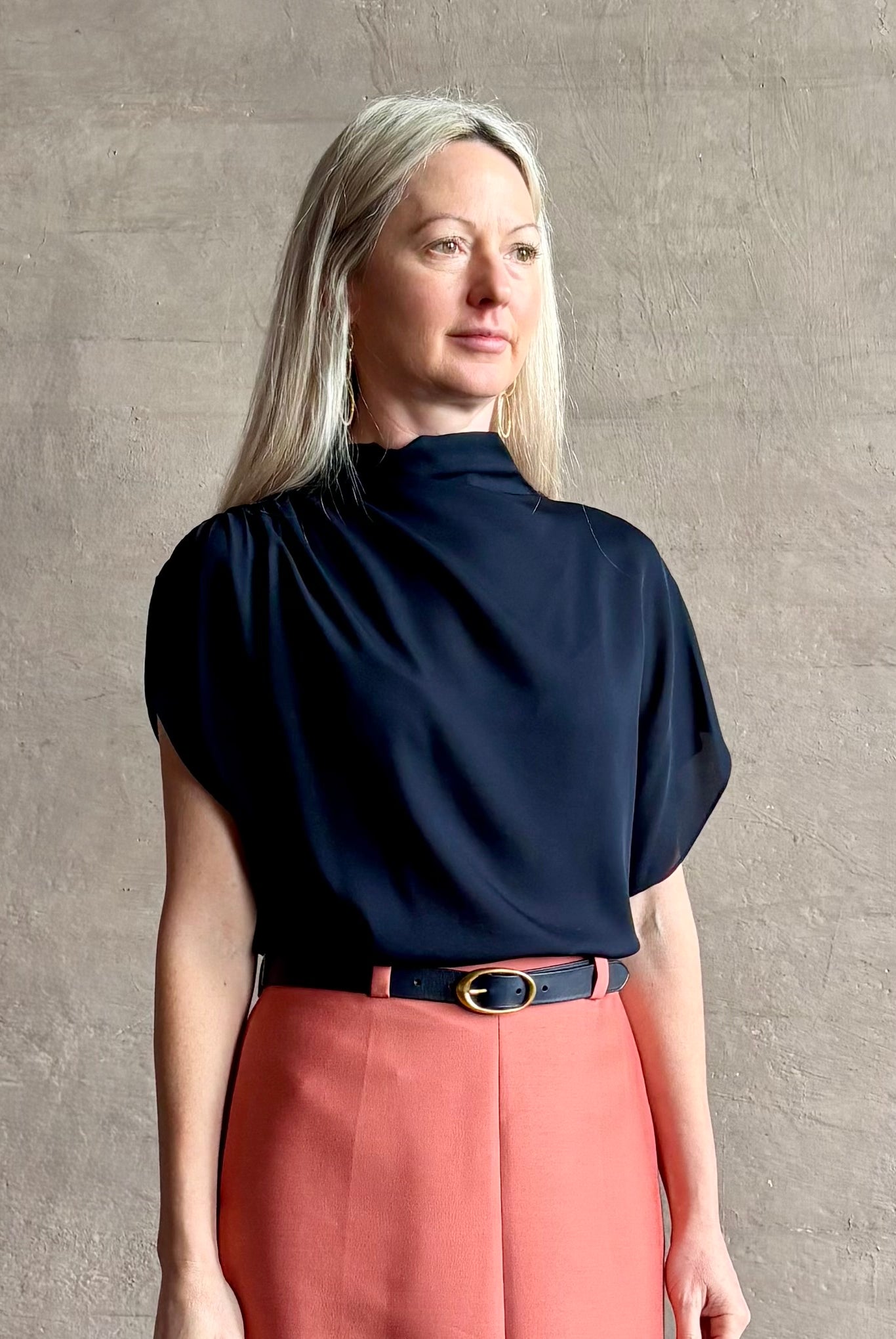Mature woman wearing an asymmetrical navy blue silk blouse by New York luxury Women's clothing designer TWP with short sleeves