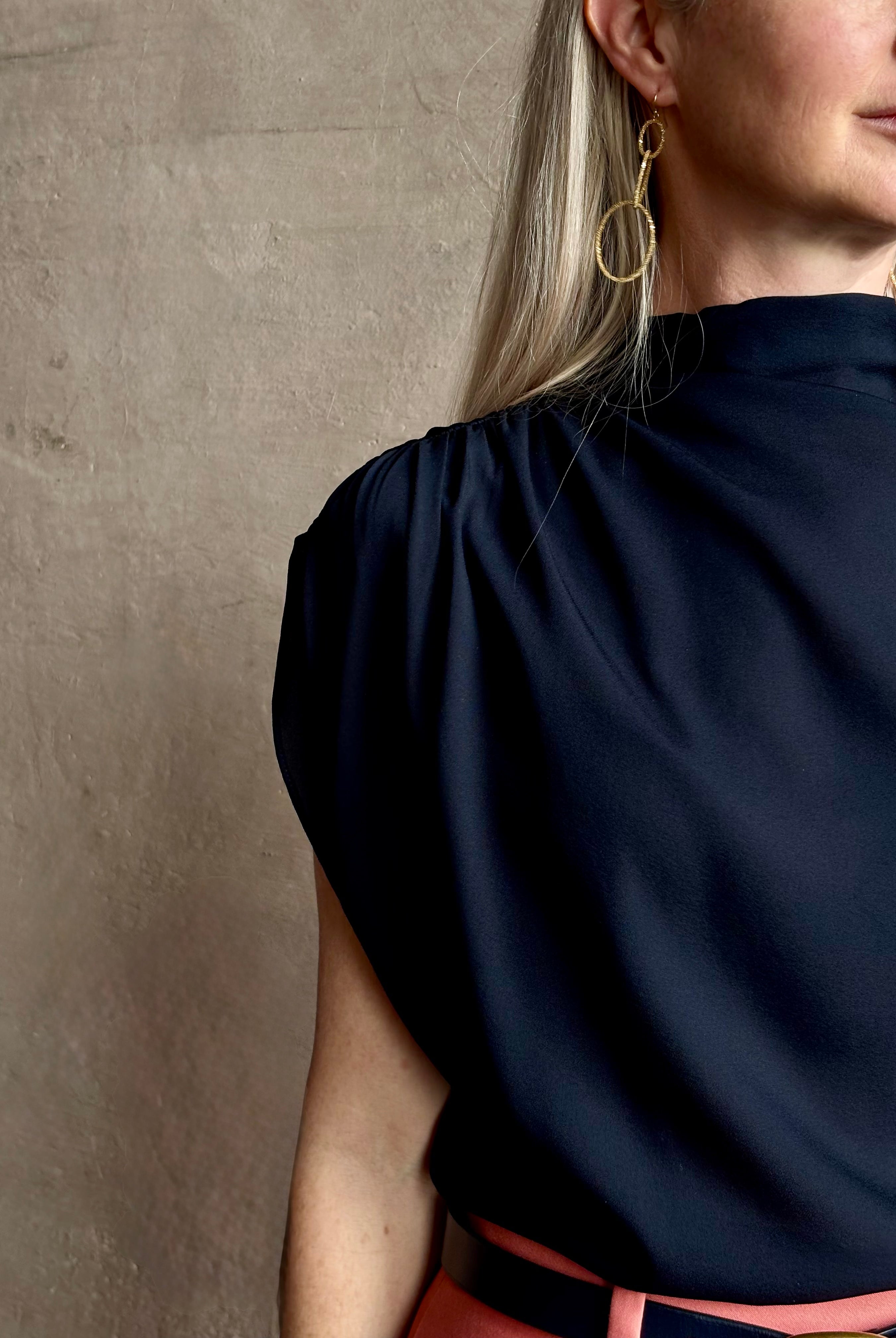 Mature woman wearing an asymmetrical navy blue silk blouse by New York luxury Women's clothing designer TWP with short sleeves