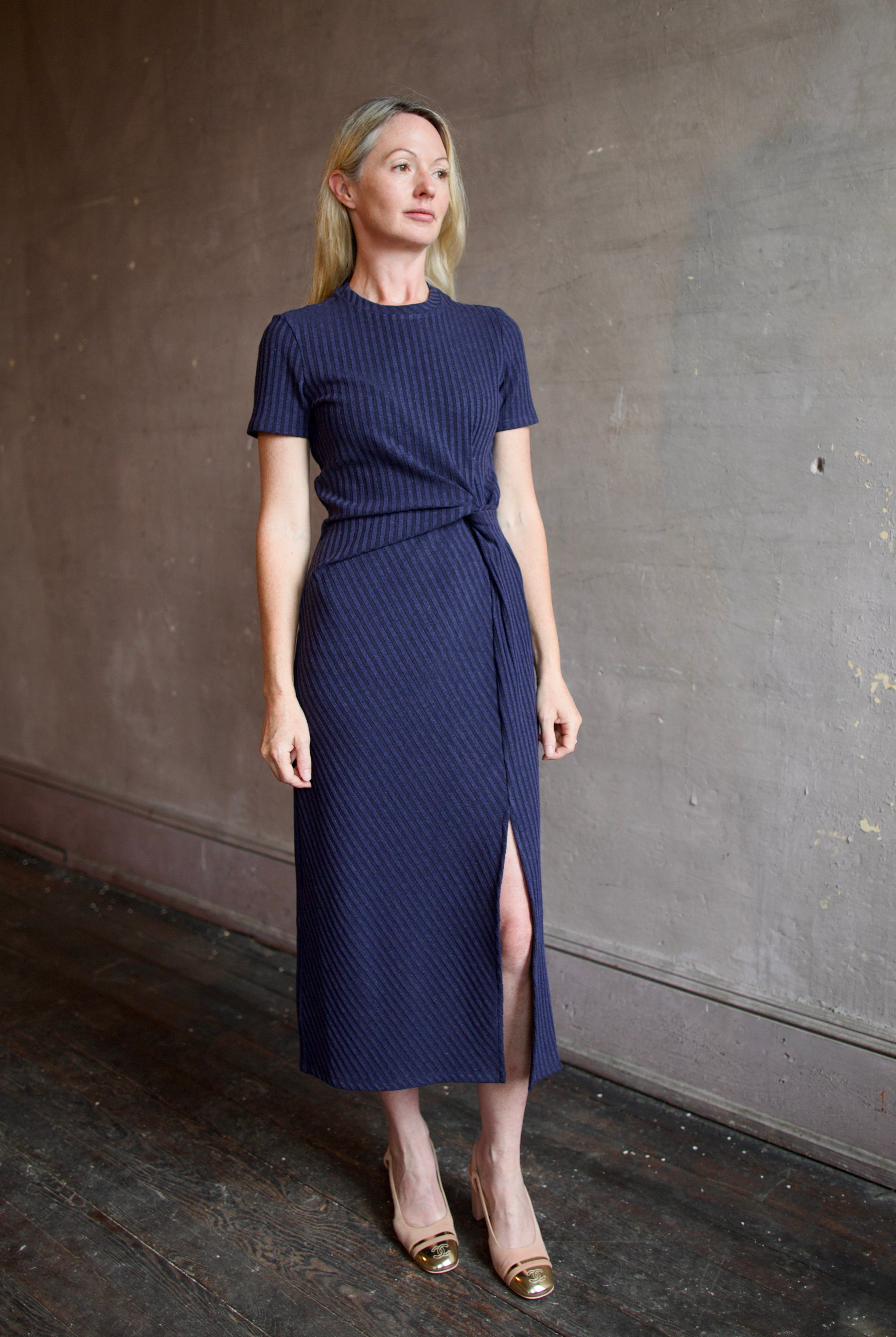 Model wearing a casual flattering navy blue dress with a twist front detail by designer Tanya Taylor
