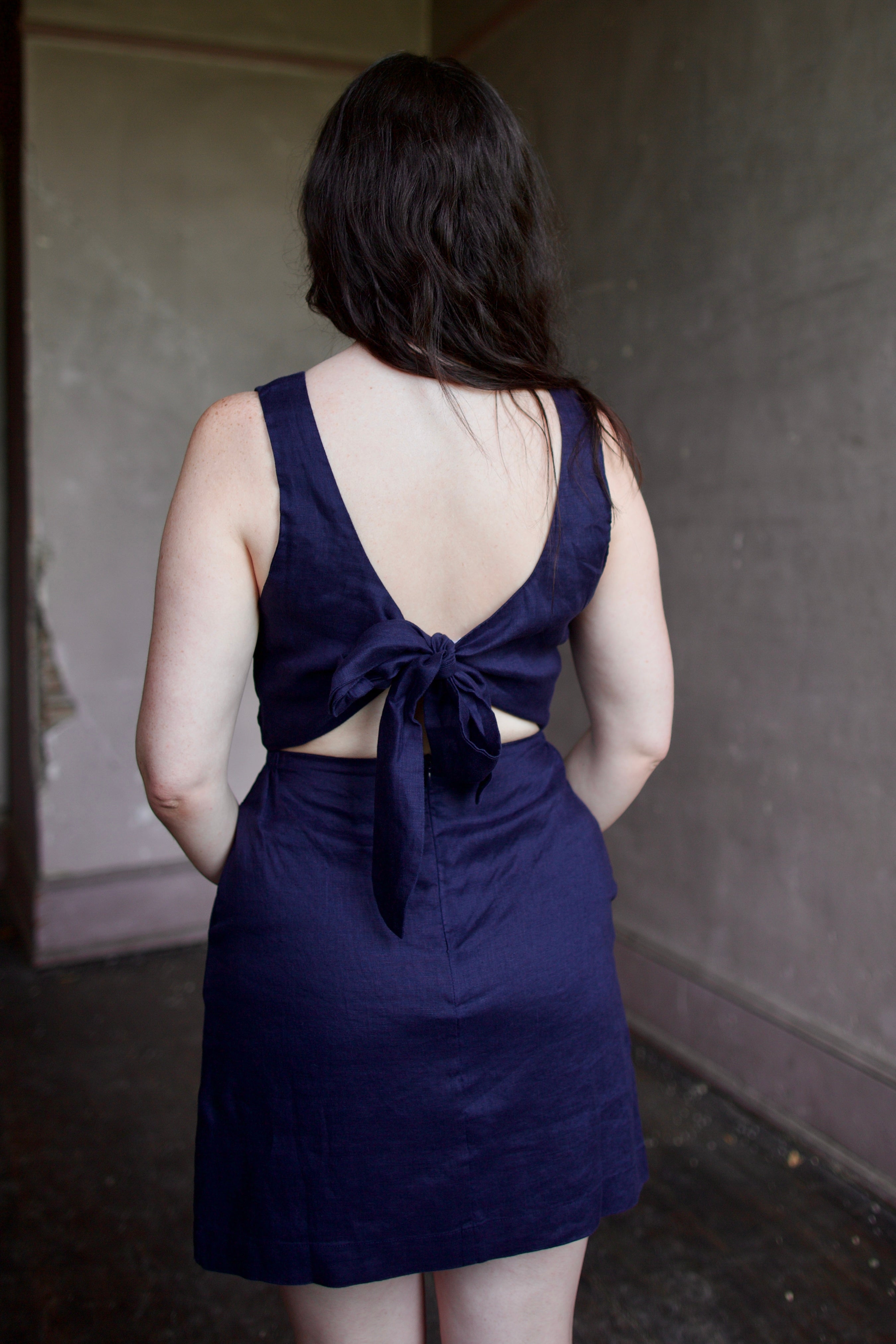 Model wearing the Trovata Rosalie linen Dress in Navy Blue with A-line skirt and sophisticated bra friendly open back