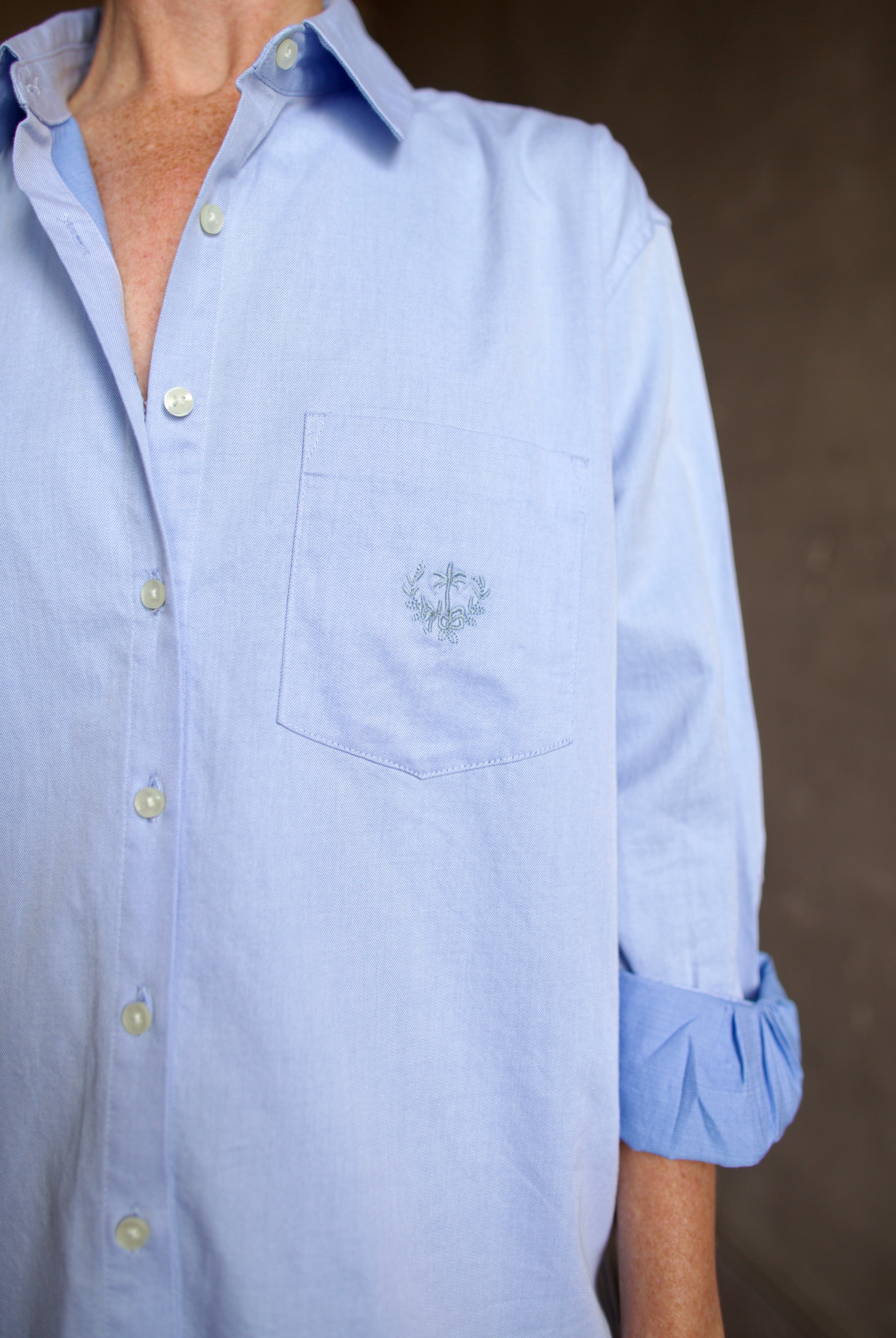 Image of model wearing the Blake light blue button-up shirt with a small embroidered design by Trovata