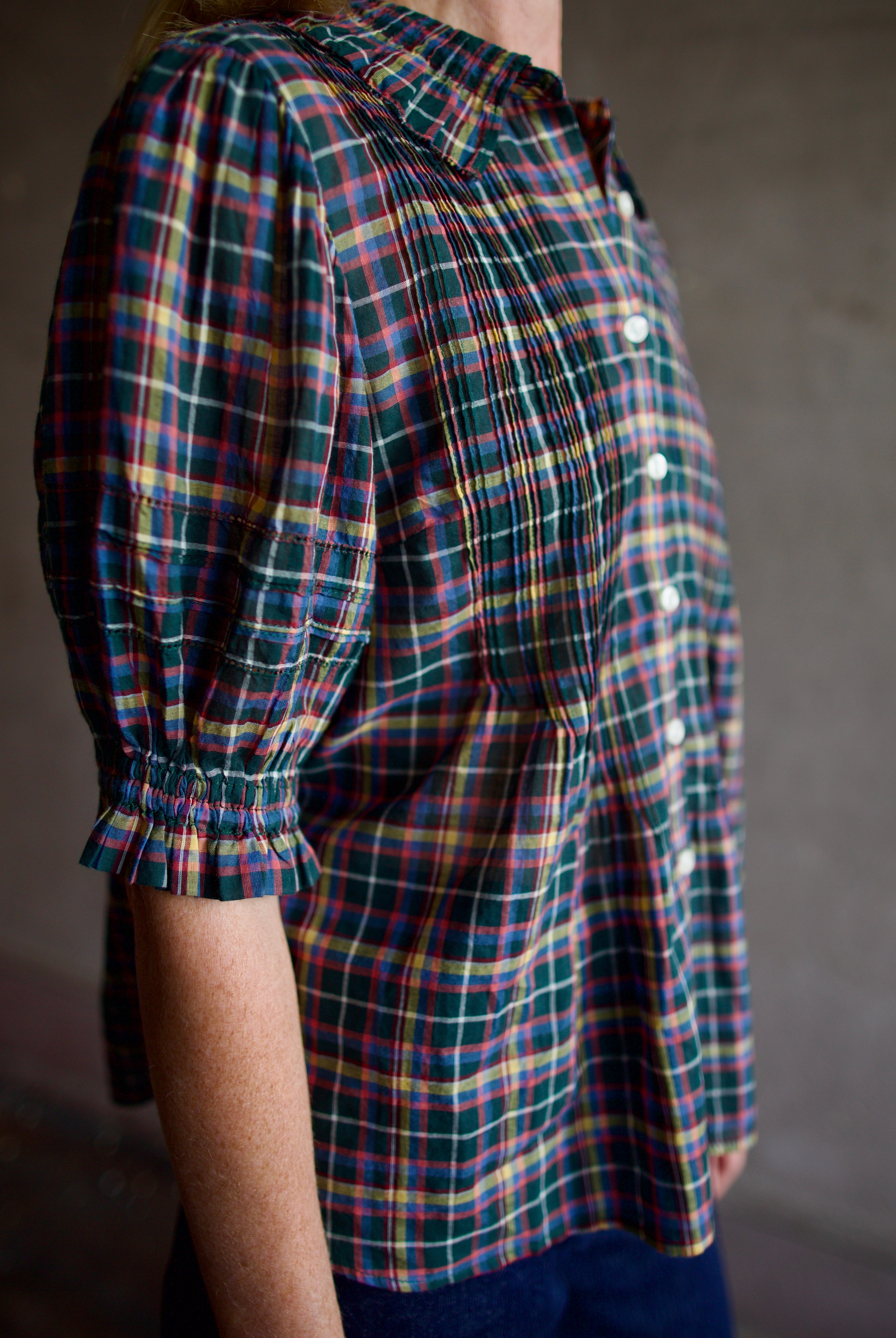 Model wearing Trovata Jess Blouse in cotton plaid with ruffle short sleeve detail pin tucking button front
