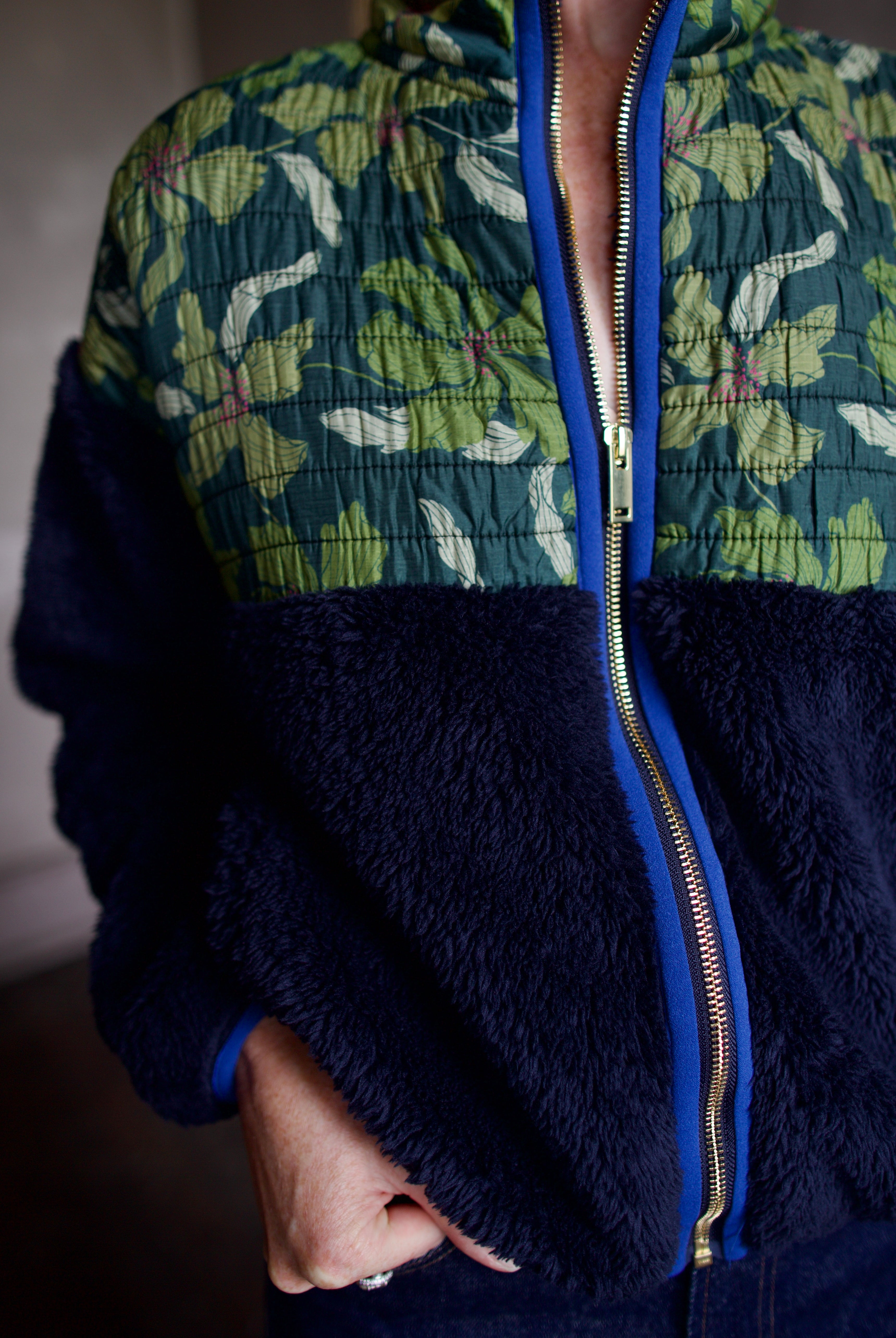 Close up image of Trovata Lennox zip-up fleece jacket in navy with a fauna green patterned panel blue trim