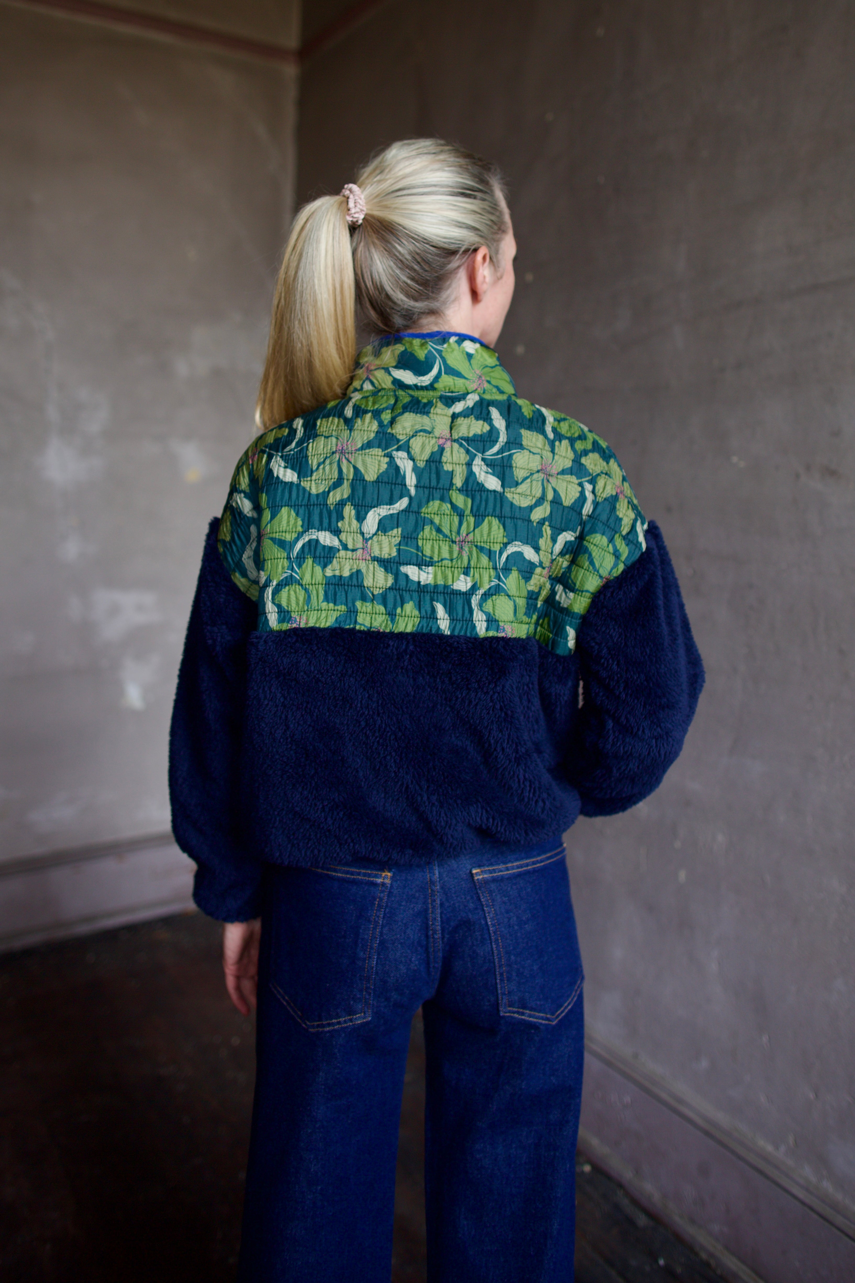 Back image of Trovata Lennox navy zip-up fleece jacket with a fauna green patterned panel