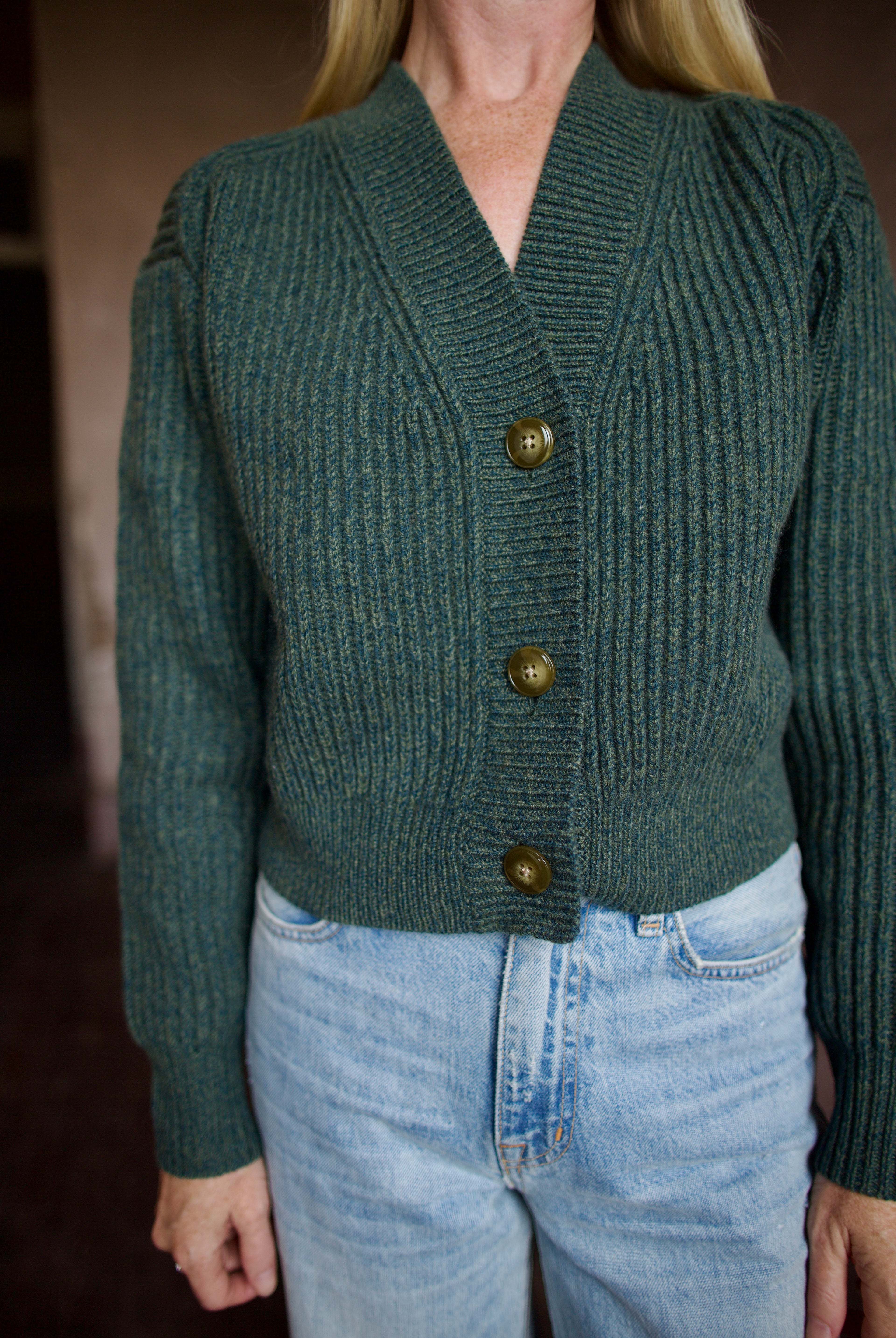 Mature wearing a green button front v neck cashmere cardigan by luxury New York brand TWP