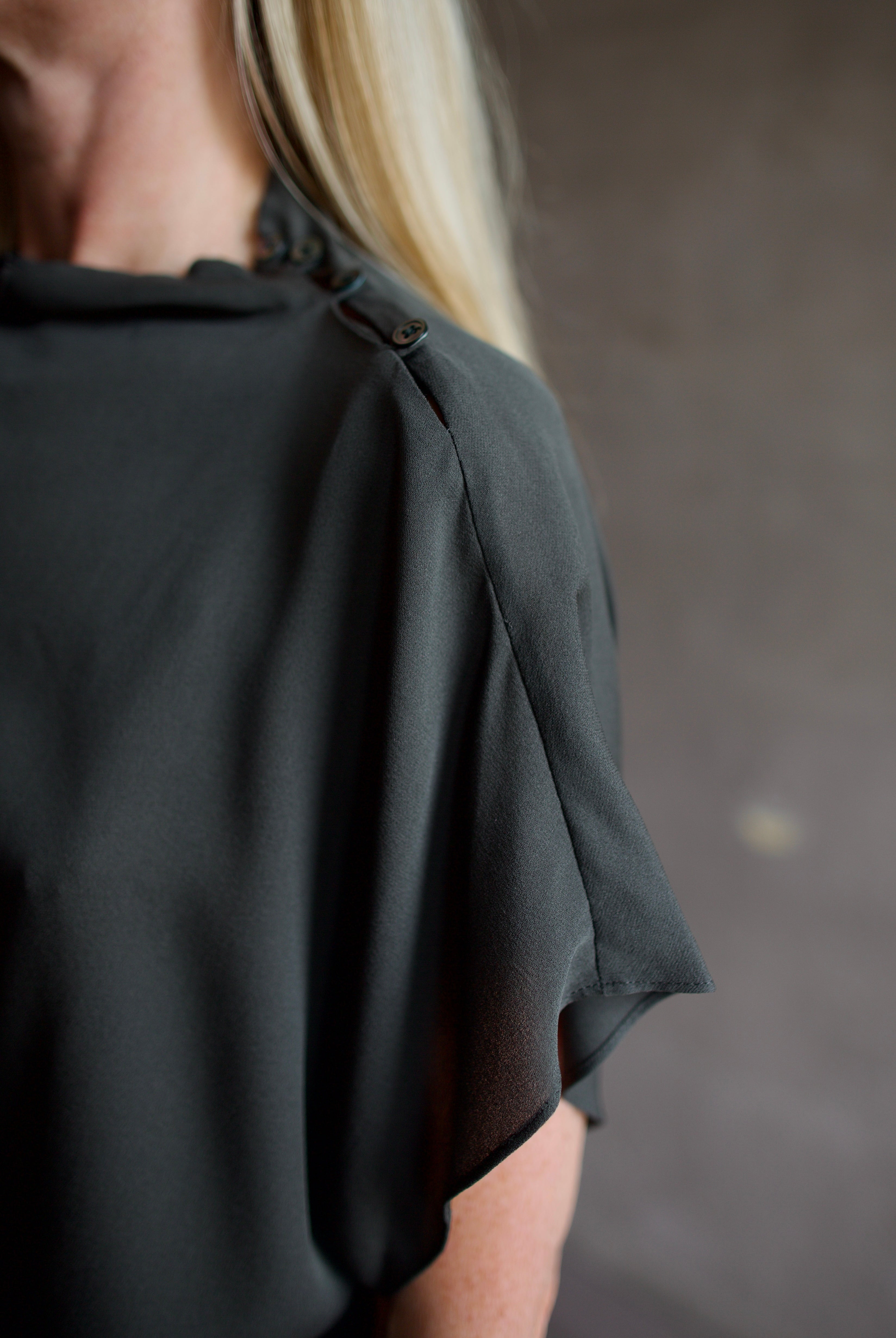 Mature model wearing a rich green TWP silk blouse with waterfall front and modern asymmetrical design