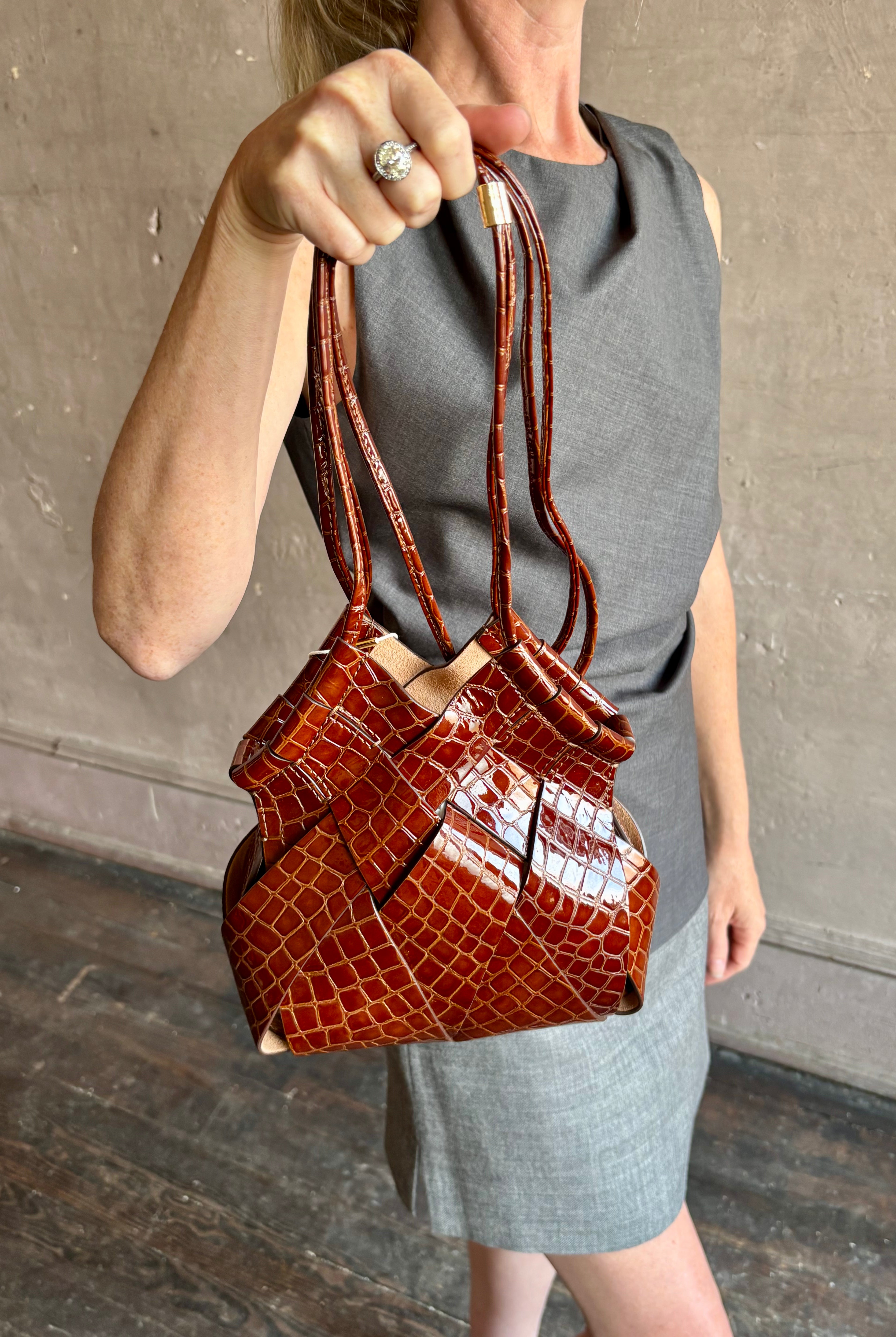Image of mature model wearing luxury designer ULLA JOHNSON Charlotte Crossbody handbag in Chestnut brown with Crocodile-Embossed leather