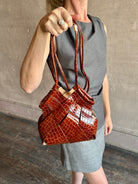 Image of mature model wearing luxury designer ULLA JOHNSON Charlotte Crossbody handbag in Chestnut brown with Crocodile-Embossed leather