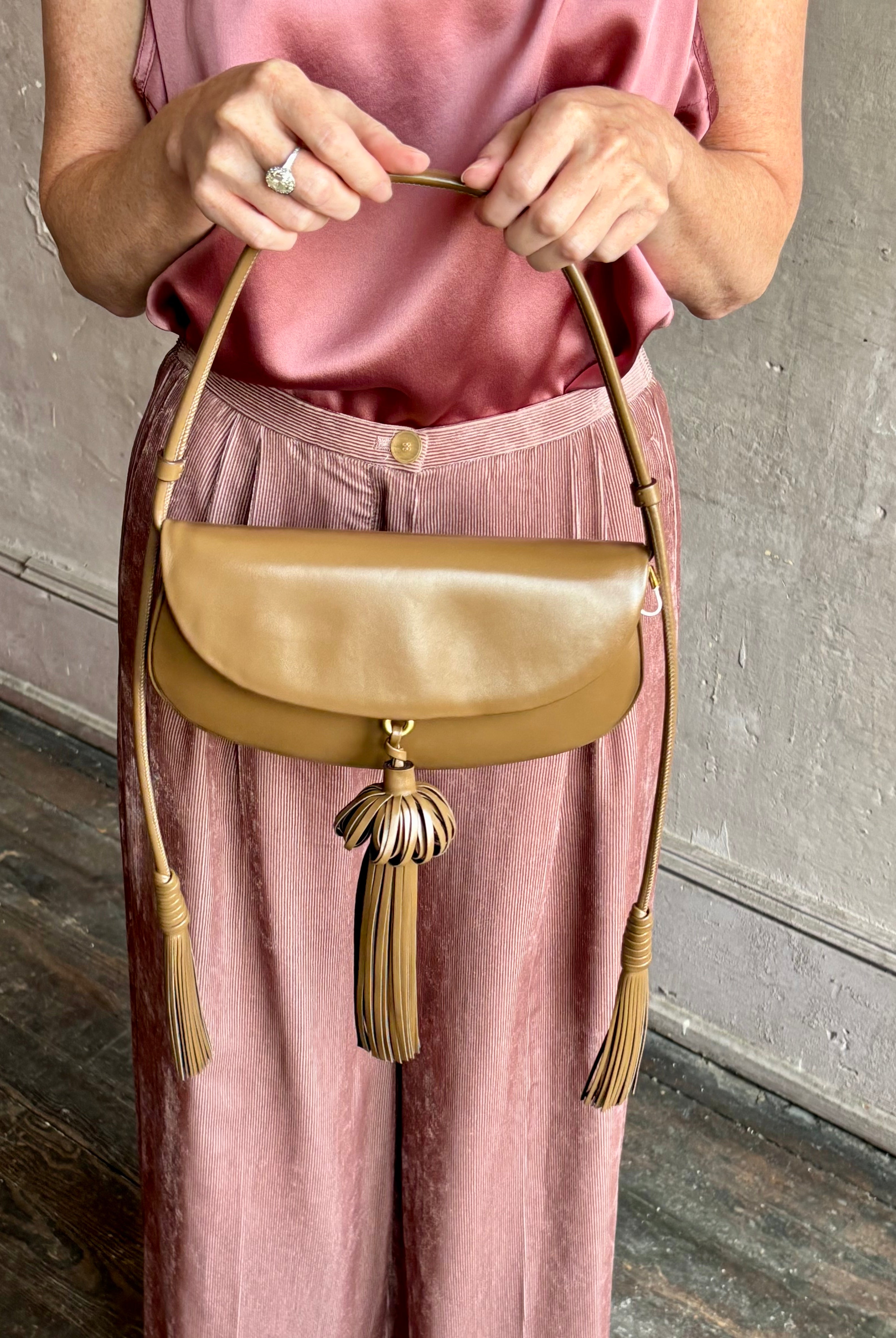 Image of mature model wearing luxury designer ULLA JOHNSON Paloma Tassel Flap leather handbag in rich brown Chestnut