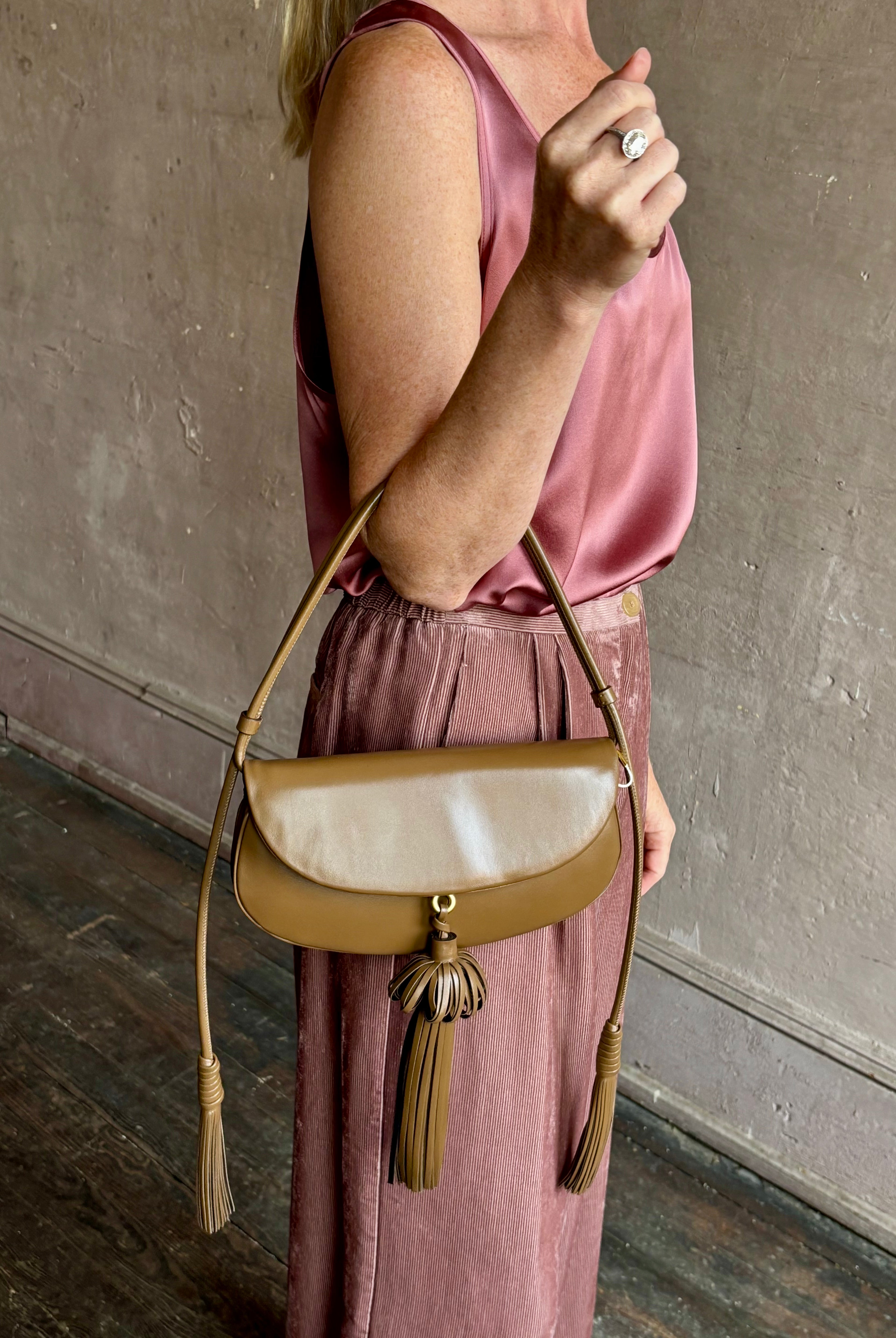 Image of mature model wearing luxury designer ULLA JOHNSON Paloma Tassel Flap leather handbag in rich brown Chestnut