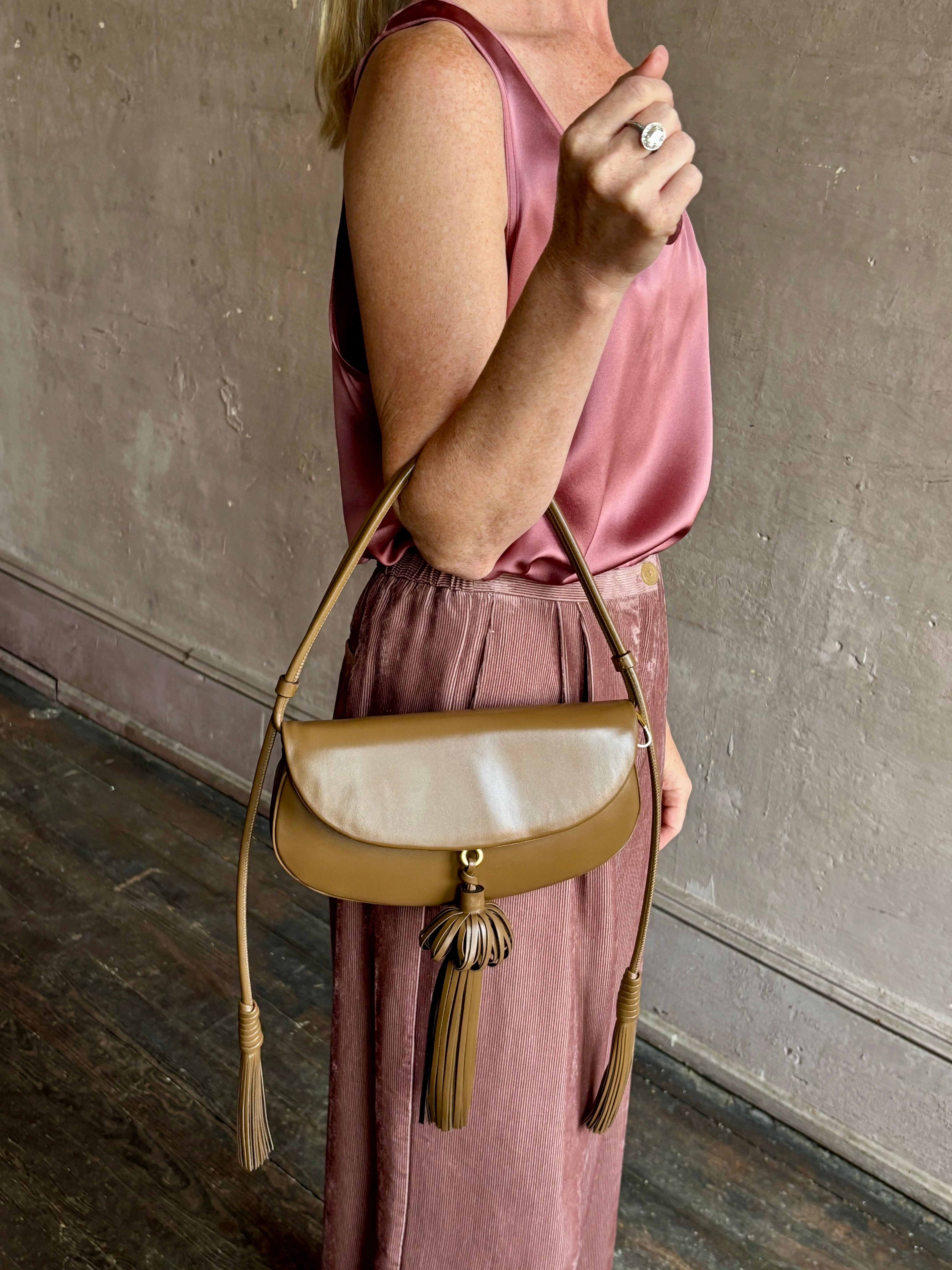 Image of mature model wearing luxury designer ULLA JOHNSON Paloma Tassel Flap leather handbag in rich brown Chestnut