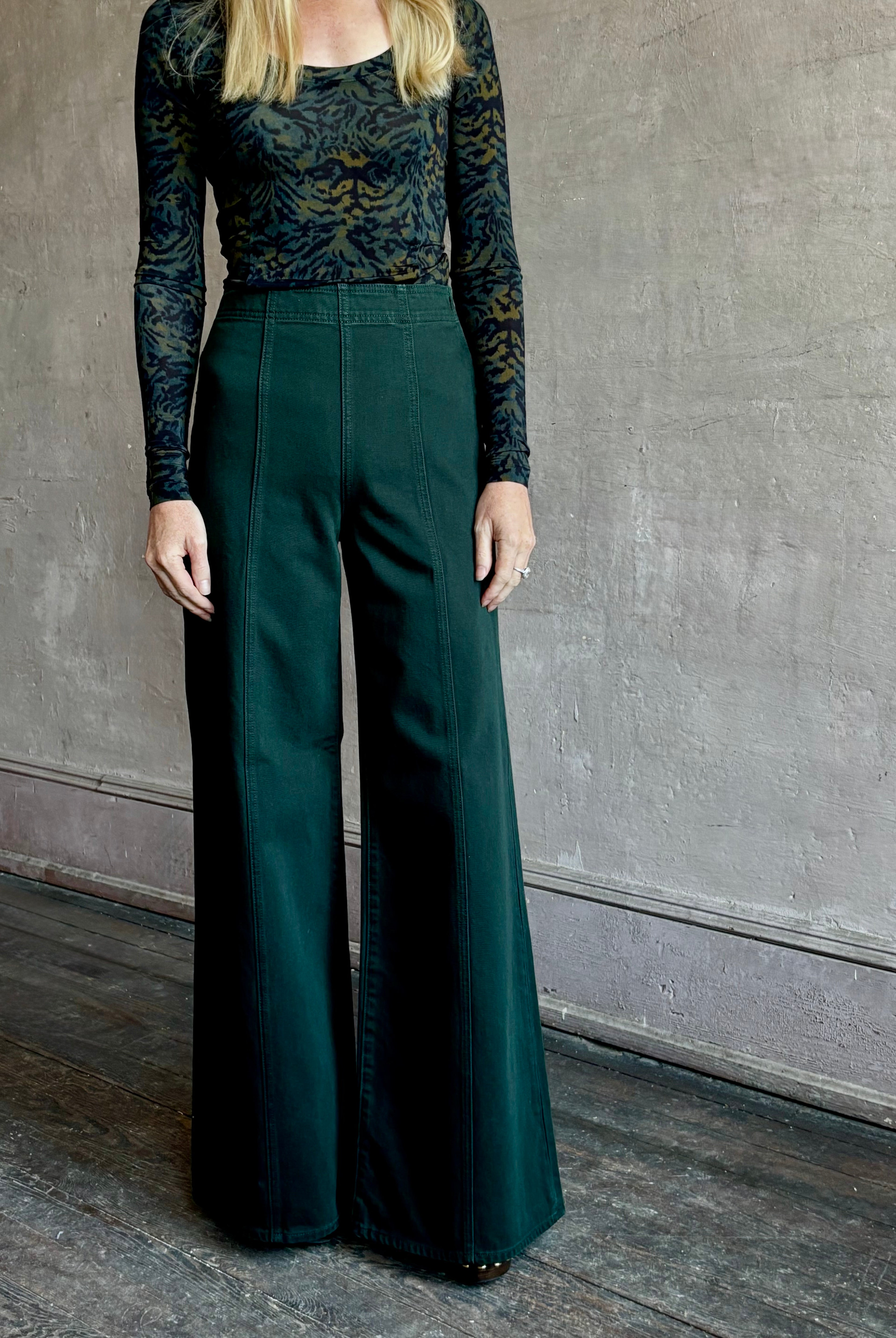 Image of woman wearing made in the USA luxury Ulla Johnson Bianca dark green denim with flat front wide leg and front seam details