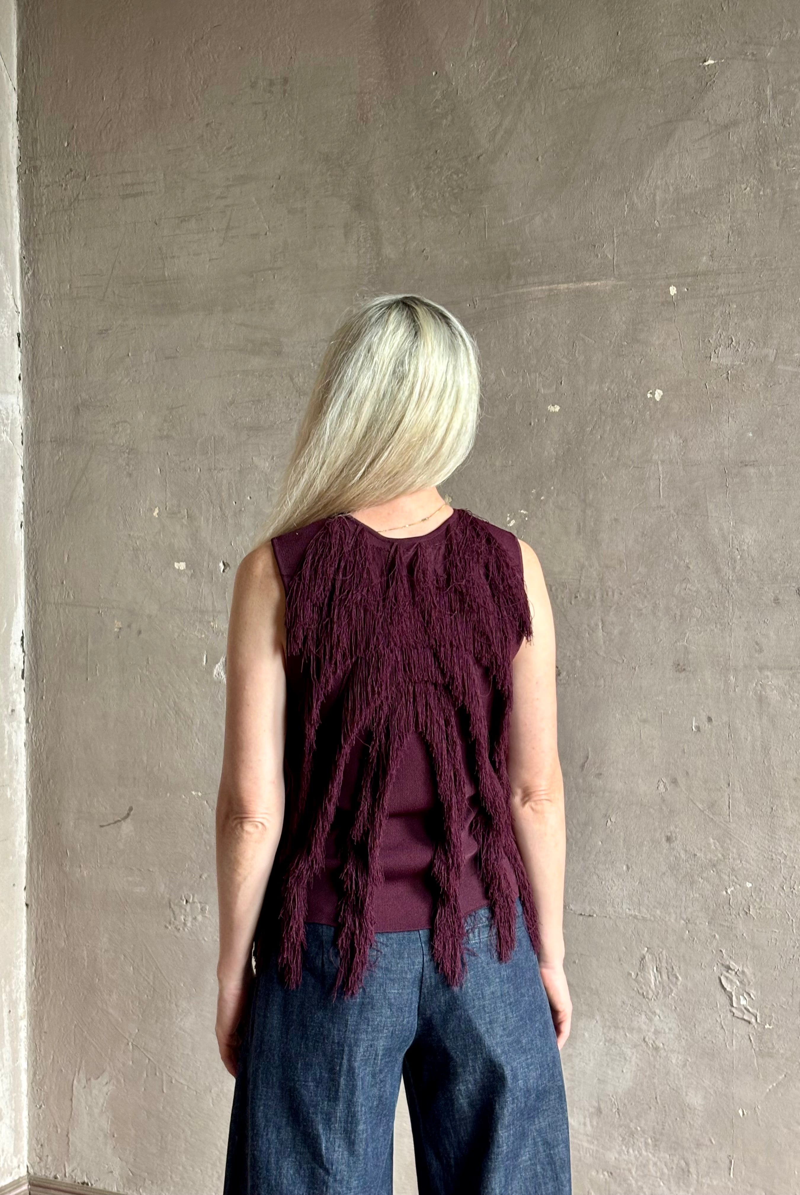 Mature woman wearing sleeveless Ulla Johnson burgundy finge knit top with fun movement in an elevated viscose blend