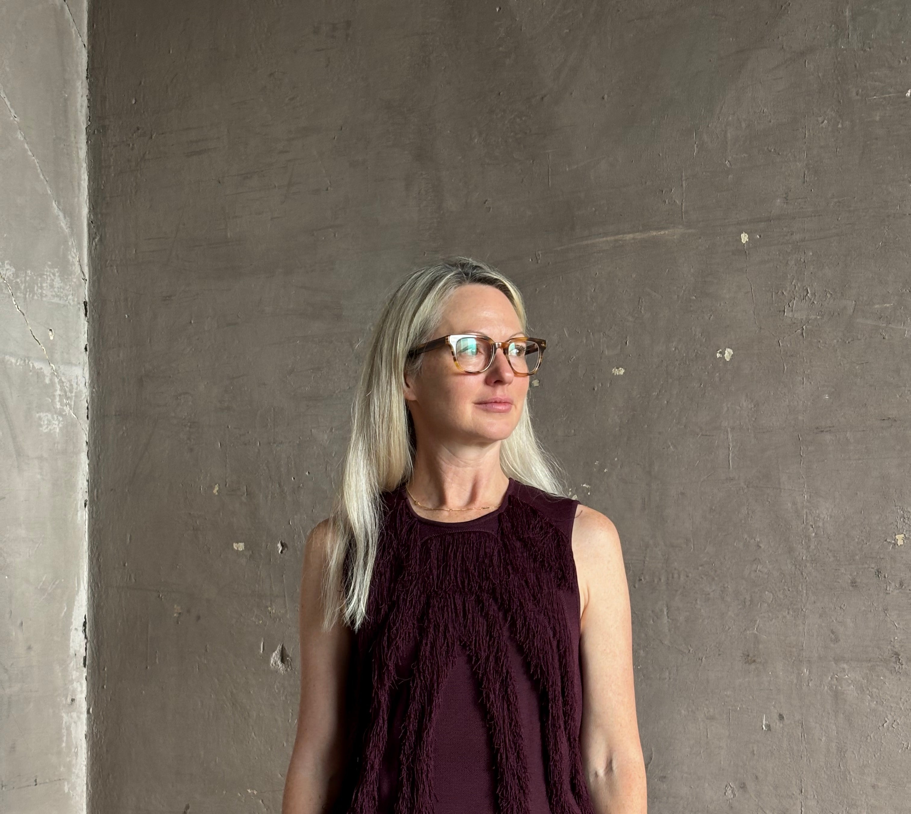 Mature woman wearing sleeveless Ulla Johnson burgundy finge knit top with fun movement in an elevated viscose blend