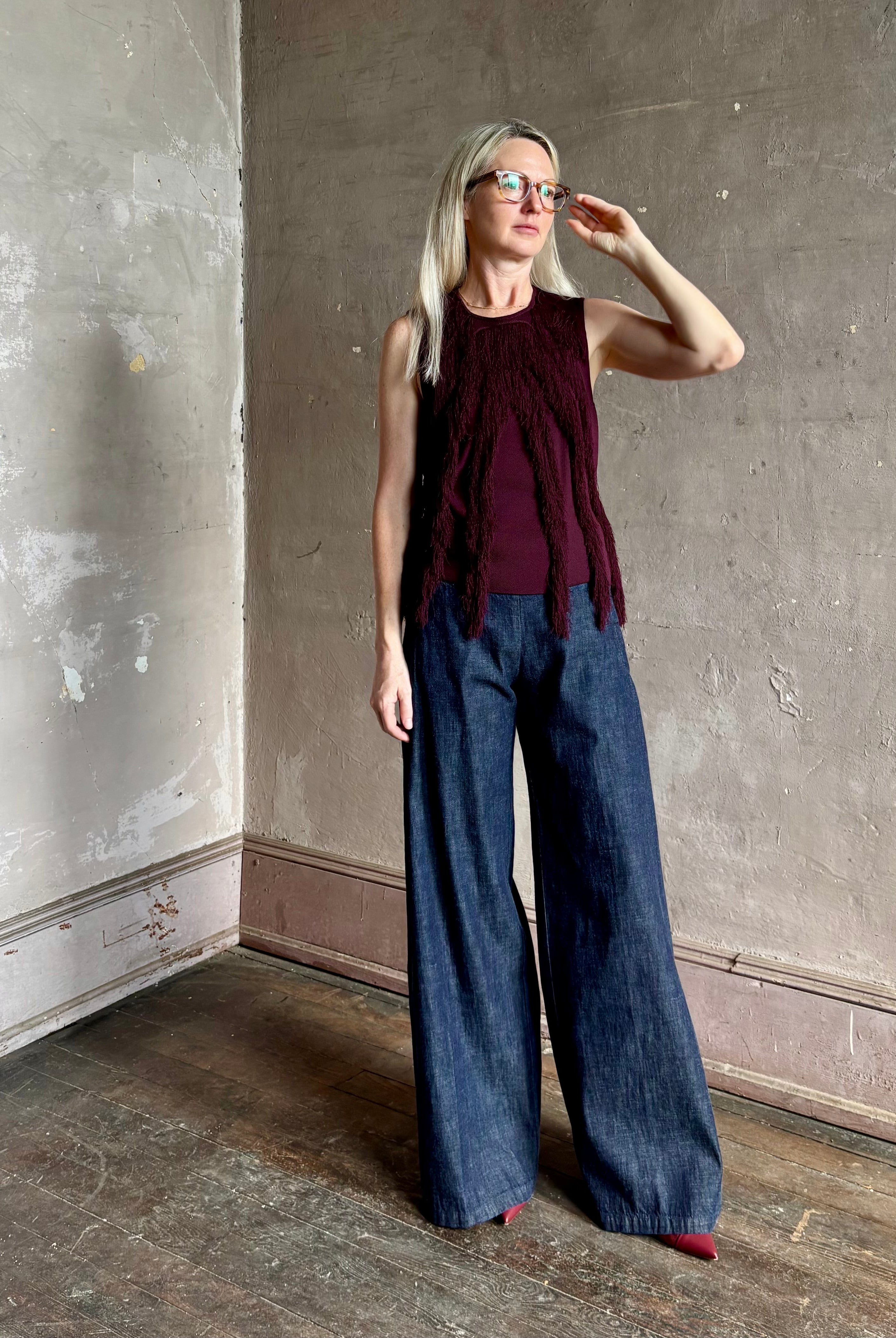 Mature woman wearing sleeveless Ulla Johnson burgundy finge knit top with fun movement in an elevated viscose blend