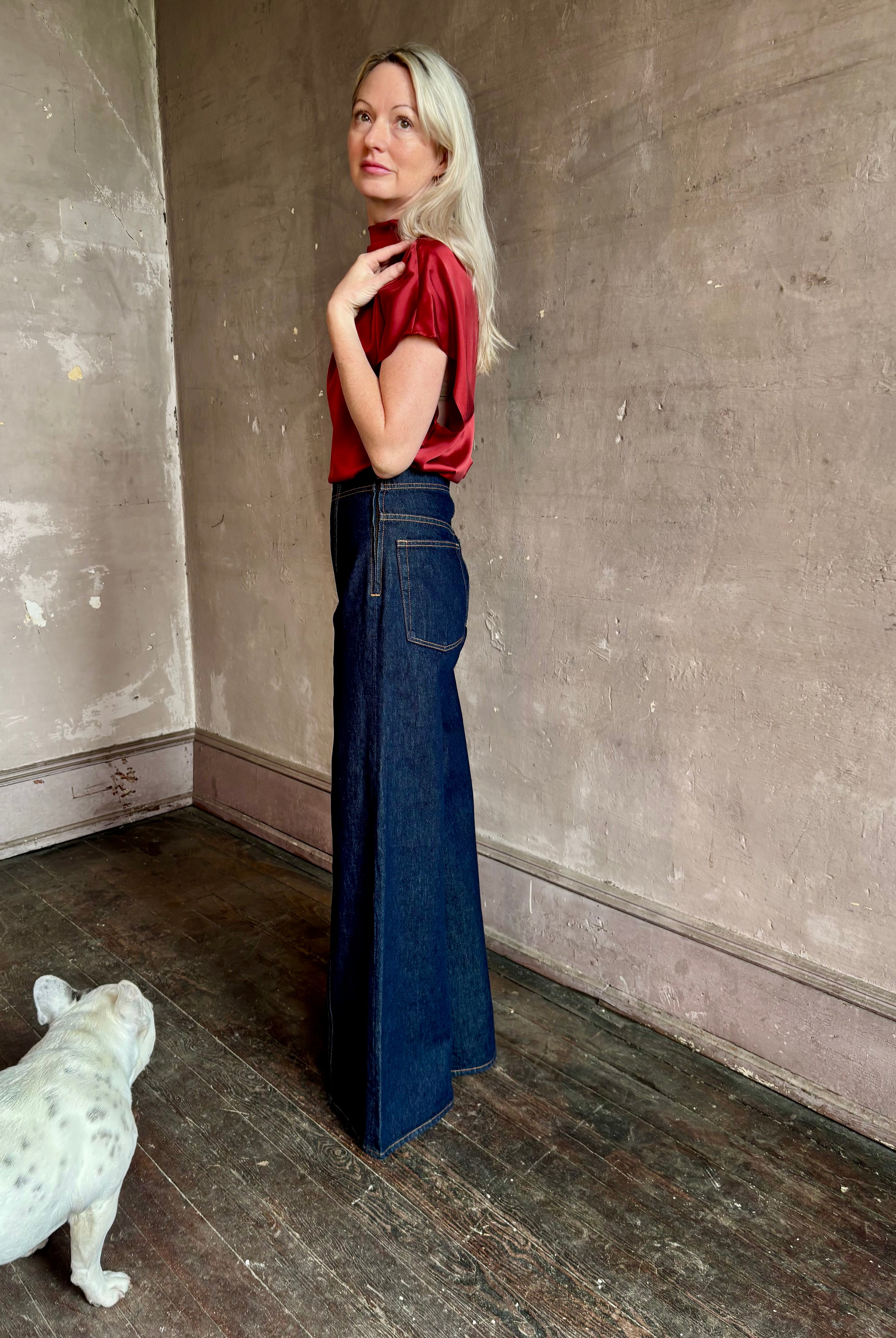 Mature woman wearing ULLA JOHNSON Bianca dark wash tigris rigid denim with a flat front, contrasting front seam details, high rise, wide leg, and side seam concealed zipper closure