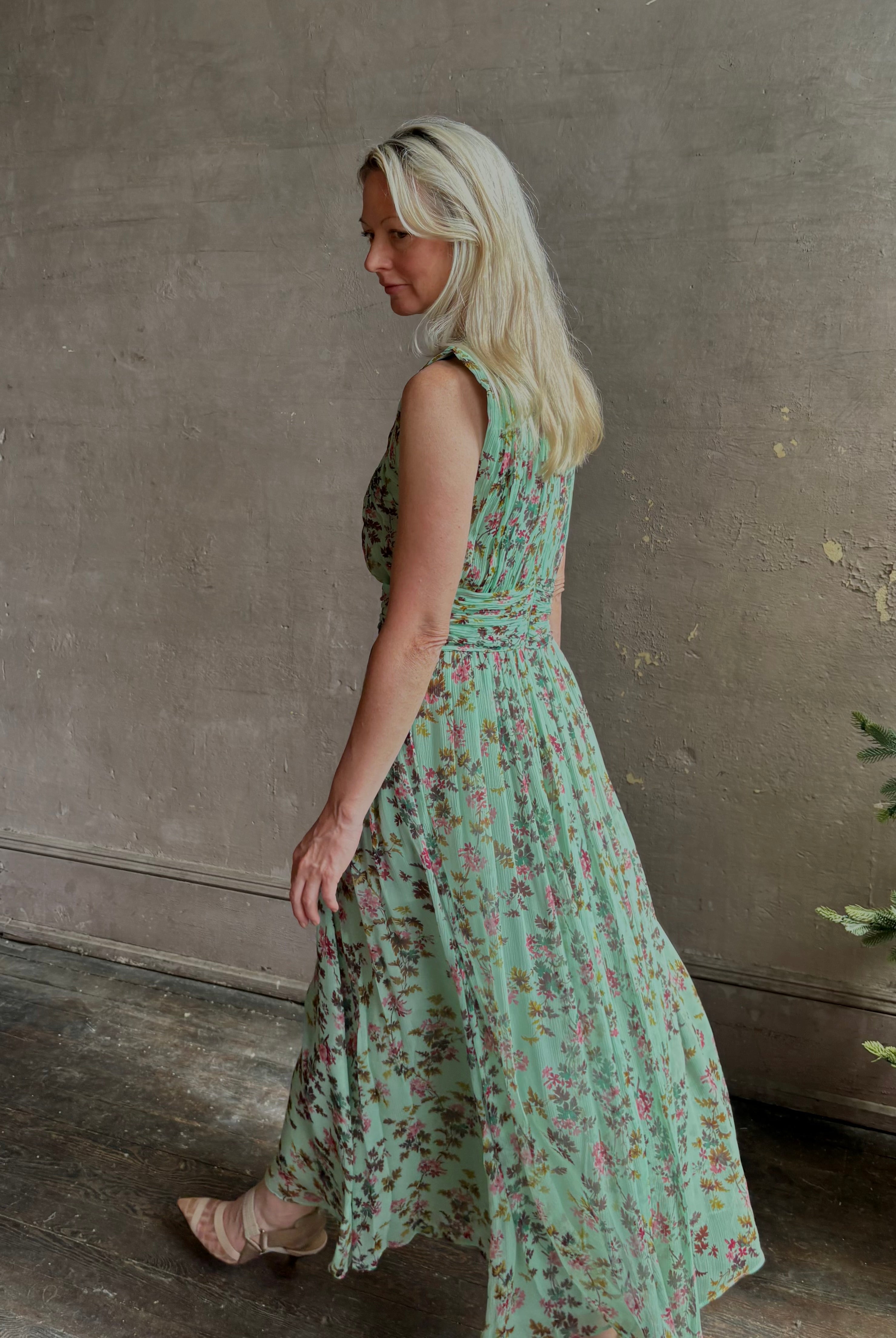 Mature woman wearing women's designer celestina silk maxi dress rendered in a mint green ground adorned with delicate brown and pink florals from Ulla Johnson that is sleevesless with gathered fabric bodice and waistband