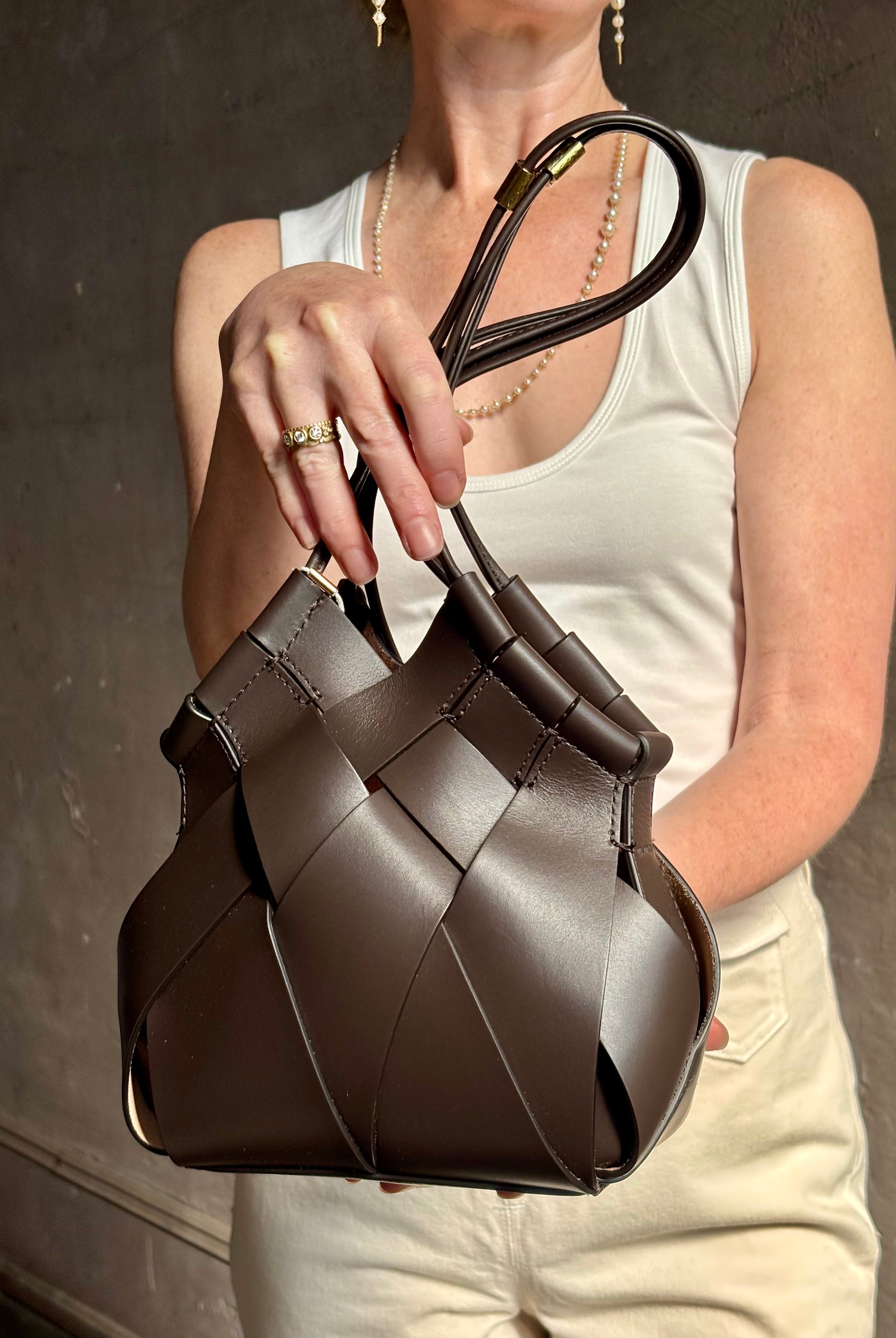 Mature woman with a Charlotte Crossbody from Ulla Johnson luxury woven Italian leather handbag rendered in a elegant neutral matte chocolate brown that easily coordinates with everything