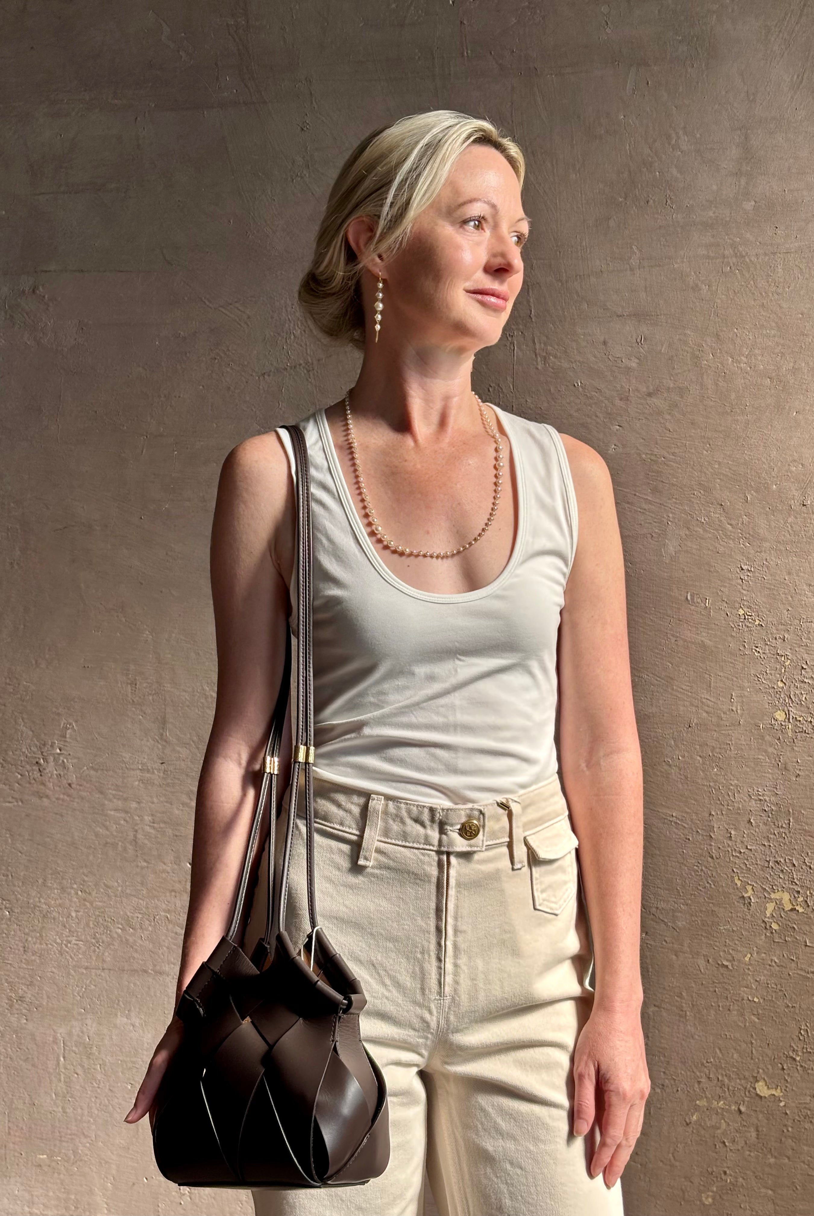 Mature woman with a Charlotte Crossbody from Ulla Johnson luxury woven Italian leather handbag rendered in a elegant neutral matte chocolate brown that easily coordinates with everything