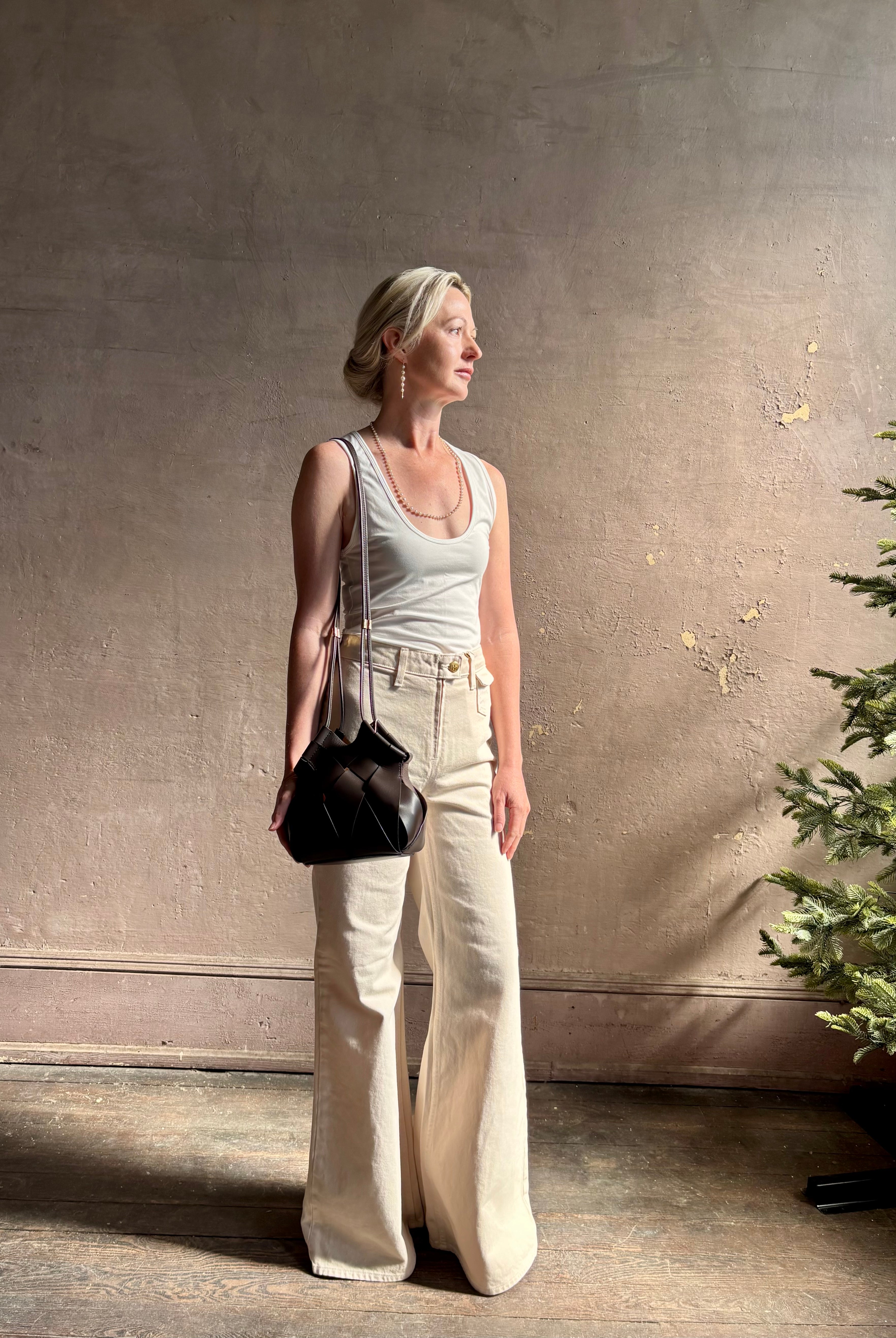Mature woman with a Charlotte Crossbody from Ulla Johnson luxury woven Italian leather handbag rendered in a elegant neutral matte chocolate brown that easily coordinates with everything