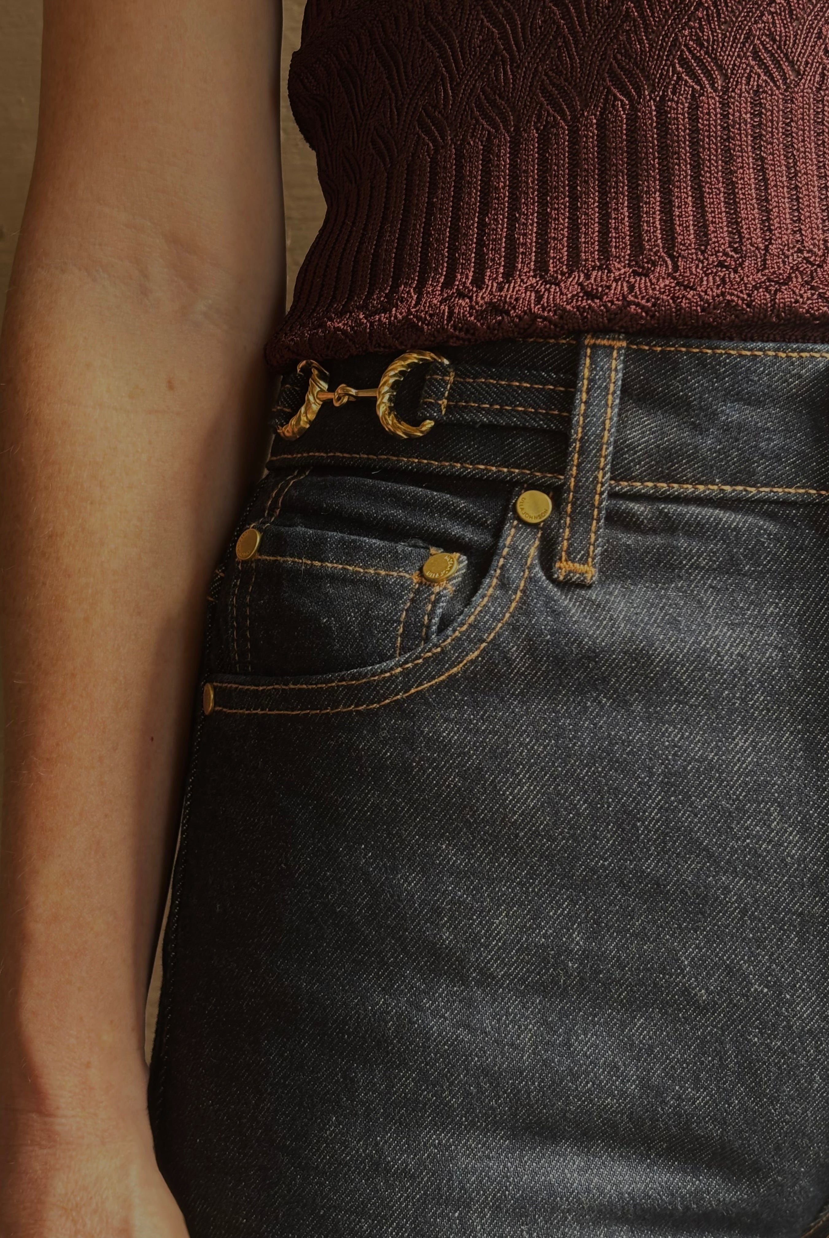 Mature woman wearing designer denim Colette Straight Leg Jean from Ulla Johnson offering American-made craftsmanship to a clean, timeless, and thoroughly modern everyday silhouette rendered in a sophisticated dark wash and crafted from 100% cotton with twisted buckle detail at waistband