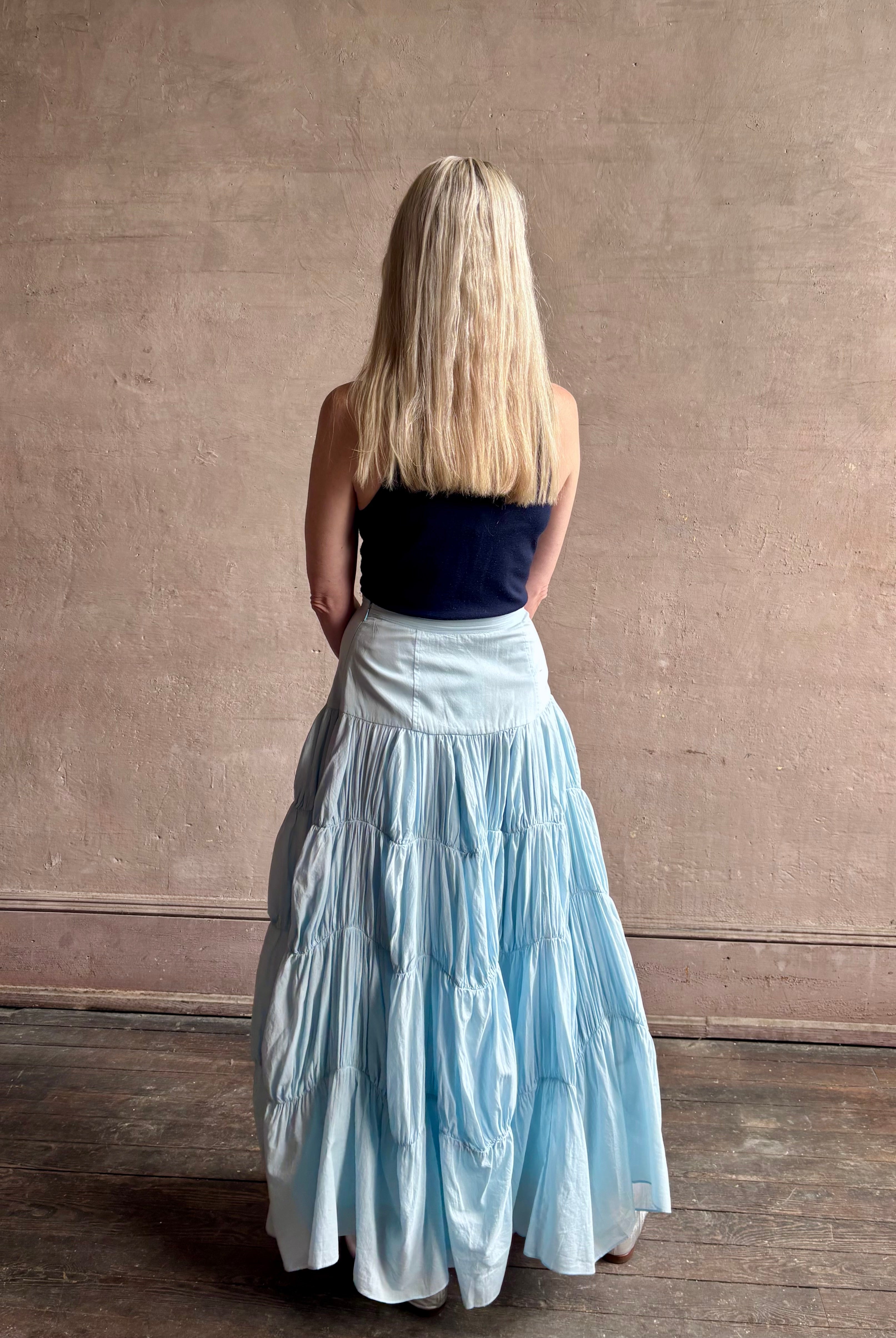 Mature woman wearing Davina Drop Waist Maxi Skirt from Ulla Johnson rendered in Adriatic Blue hue with intricate full skirt ruching