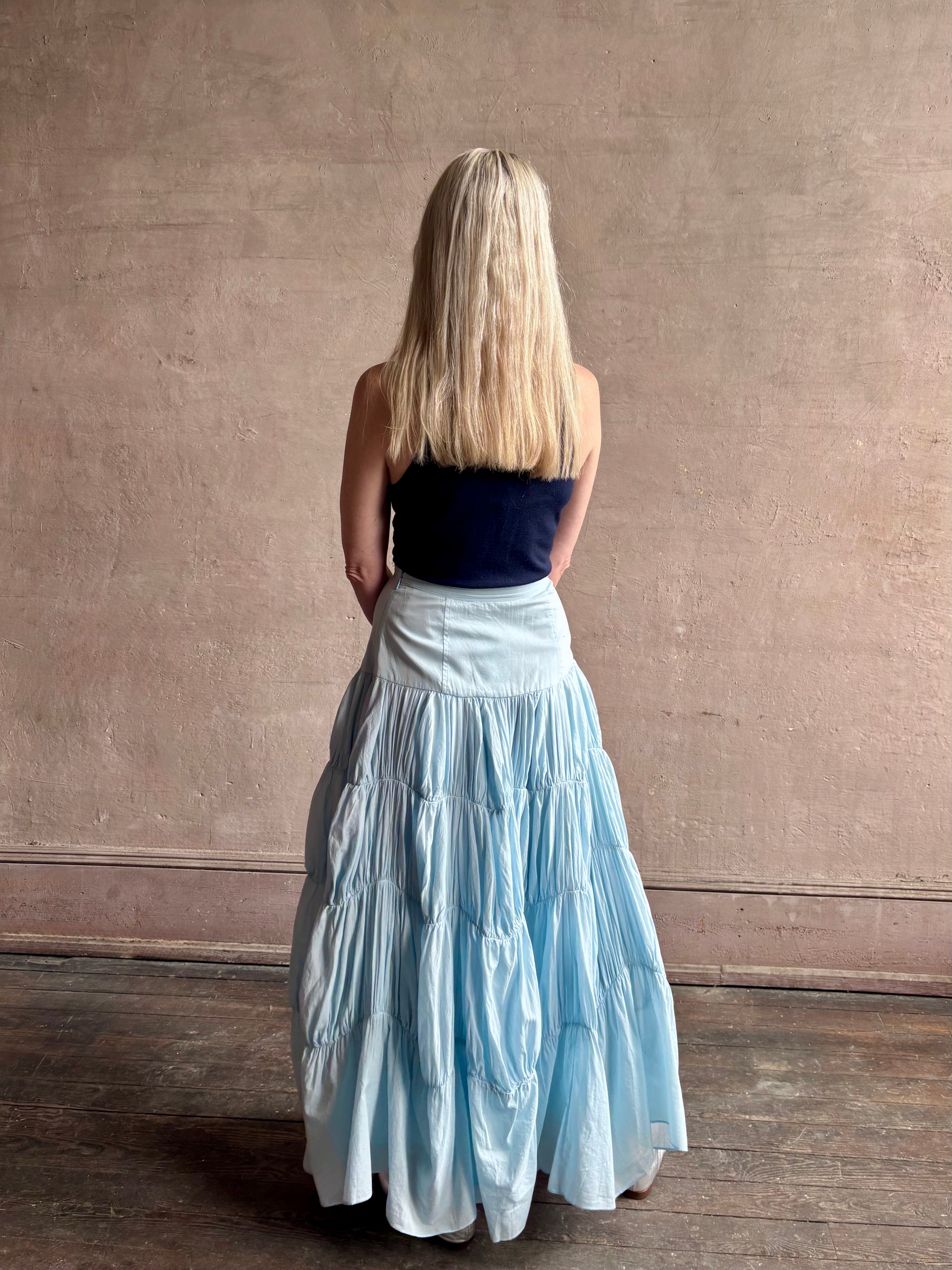 Mature woman wearing Davina Drop Waist Maxi Skirt from Ulla Johnson rendered in Adriatic Blue hue with intricate full skirt ruching