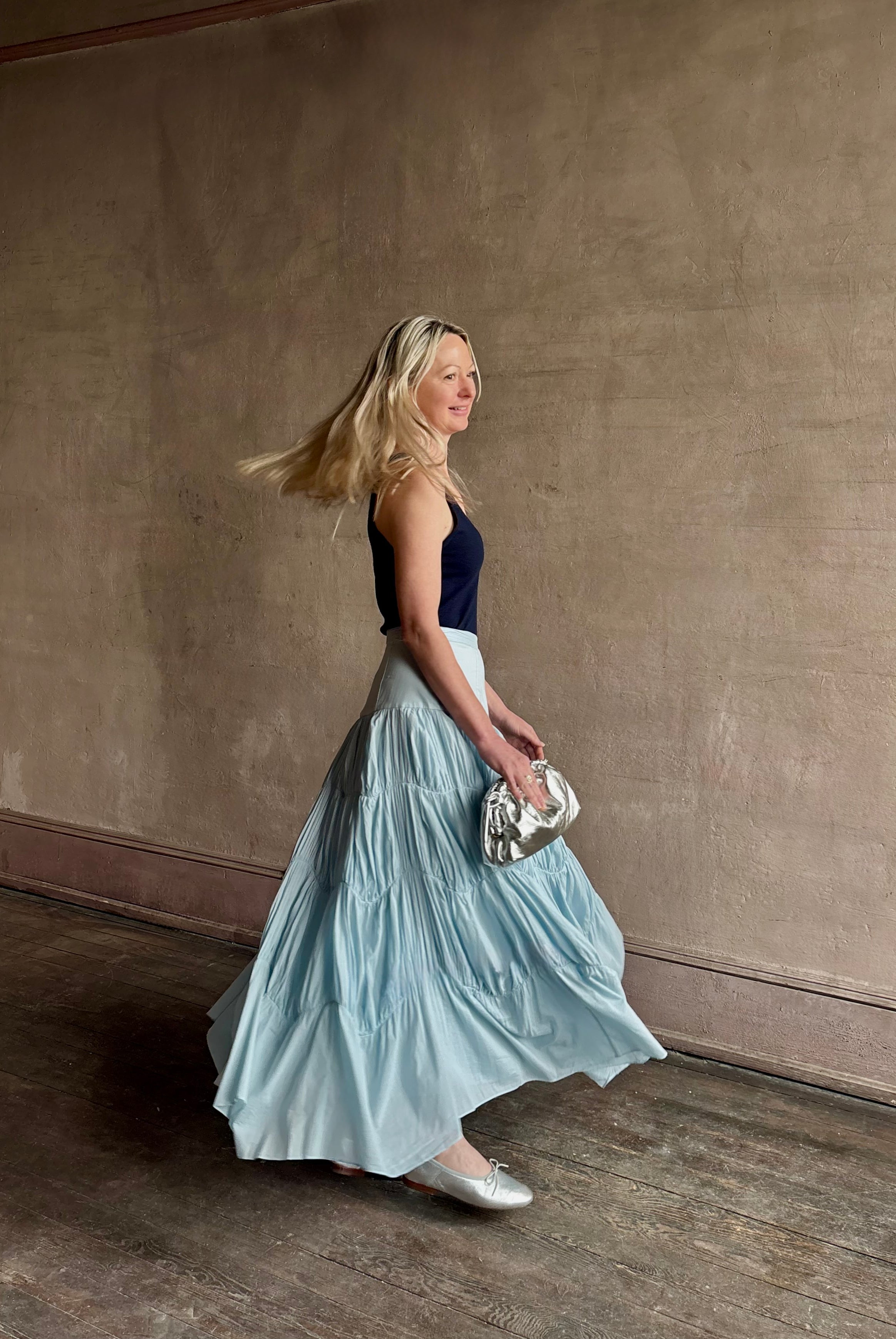 Mature woman wearing Davina Drop Waist Maxi Skirt from Ulla Johnson rendered in Adriatic Blue hue with intricate full skirt ruching