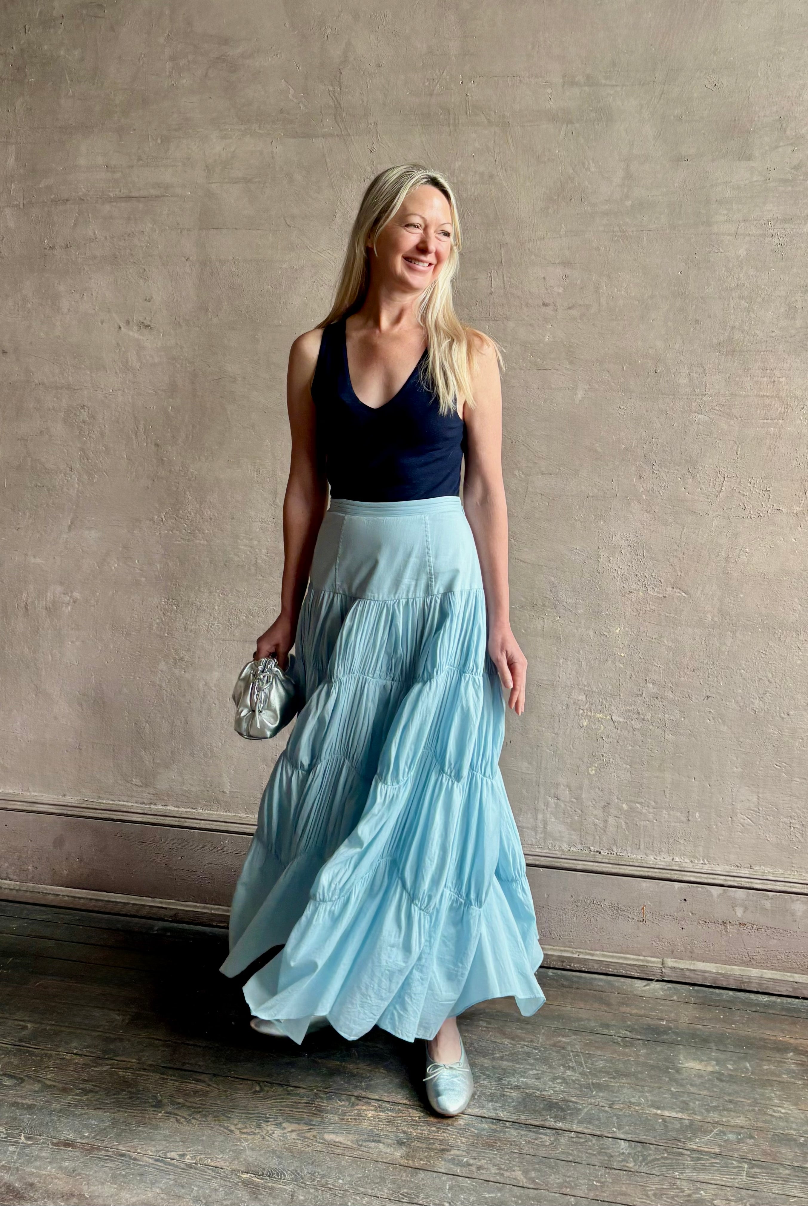 Mature woman wearing Davina Drop Waist Maxi Skirt from Ulla Johnson rendered in Adriatic Blue hue with intricate full skirt ruching