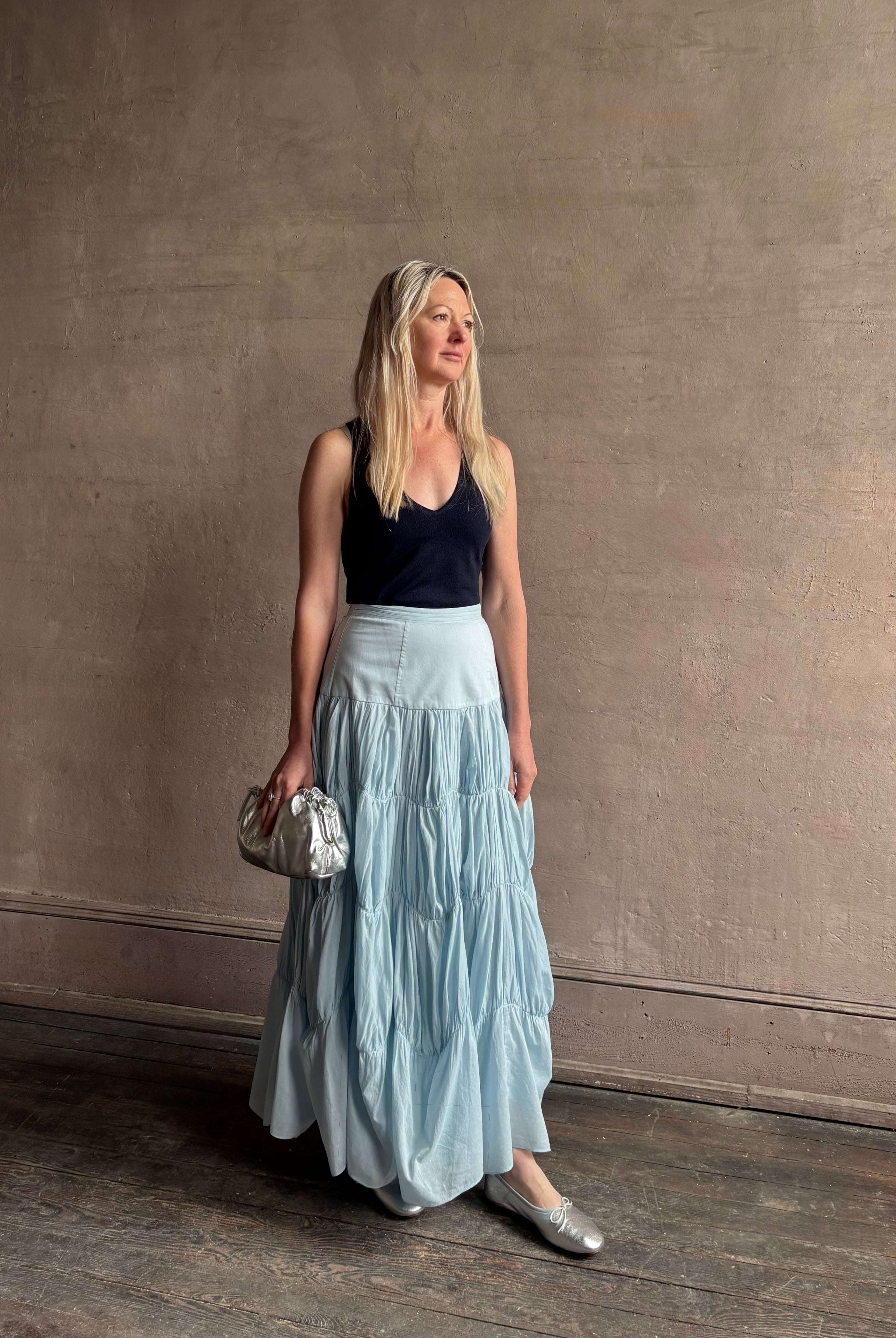 Mature woman wearing Davina Drop Waist Maxi Skirt from Ulla Johnson rendered in Adriatic Blue hue with intricate full skirt ruching