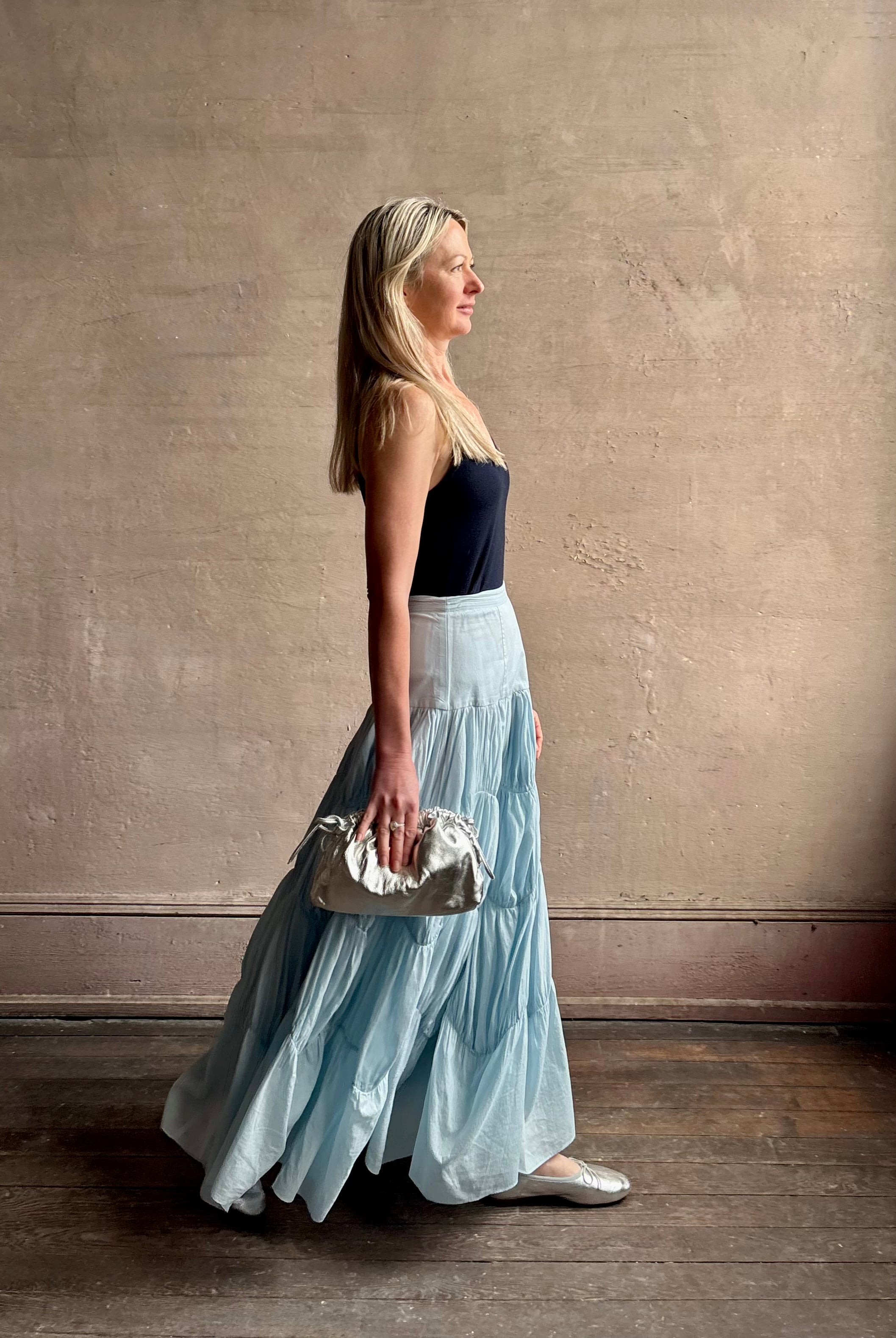 Mature woman wearing Davina Drop Waist Maxi Skirt from Ulla Johnson rendered in Adriatic Blue hue with intricate full skirt ruching