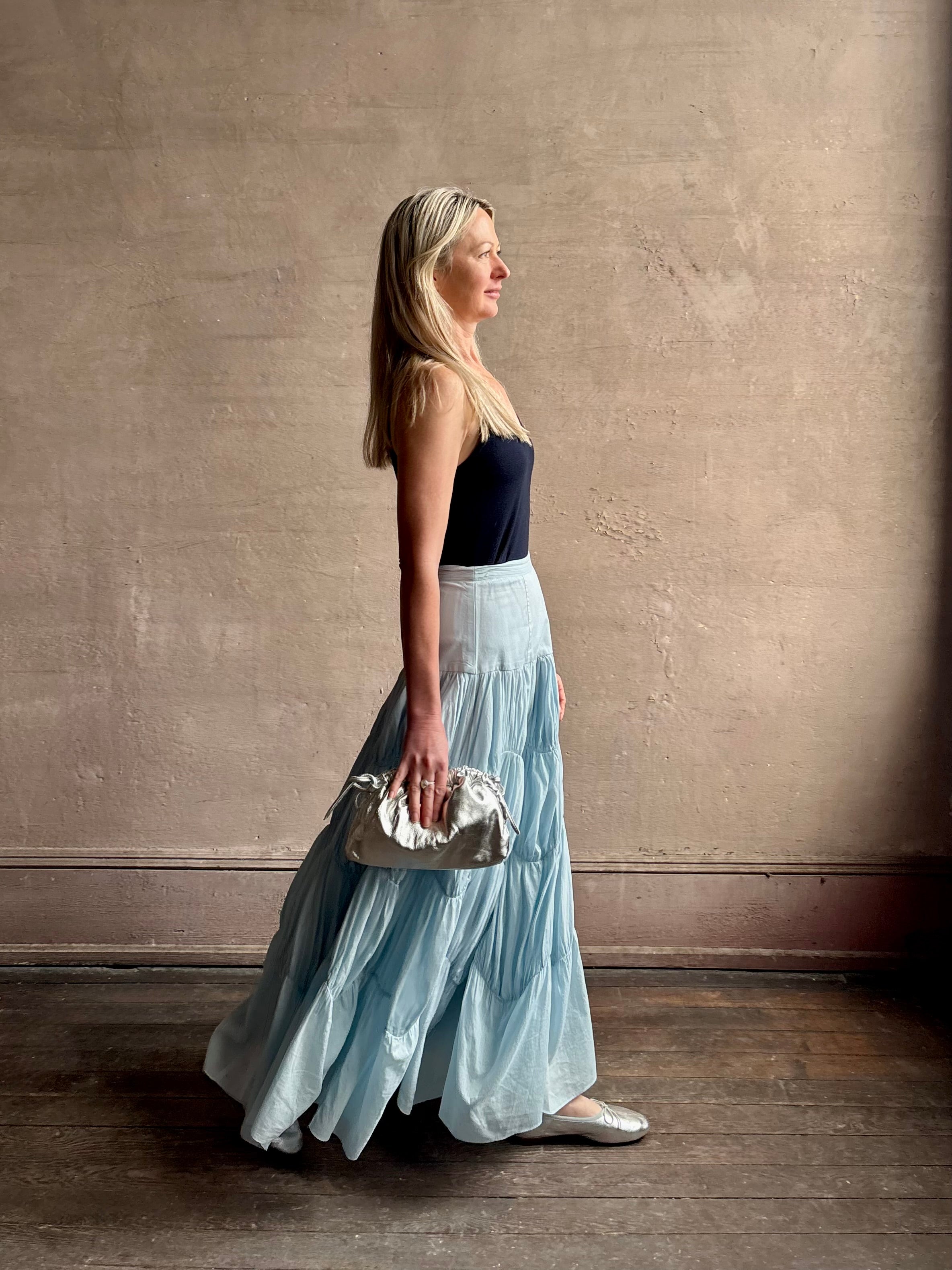 Mature woman wearing Davina Drop Waist Maxi Skirt from Ulla Johnson rendered in Adriatic Blue hue with intricate full skirt ruching