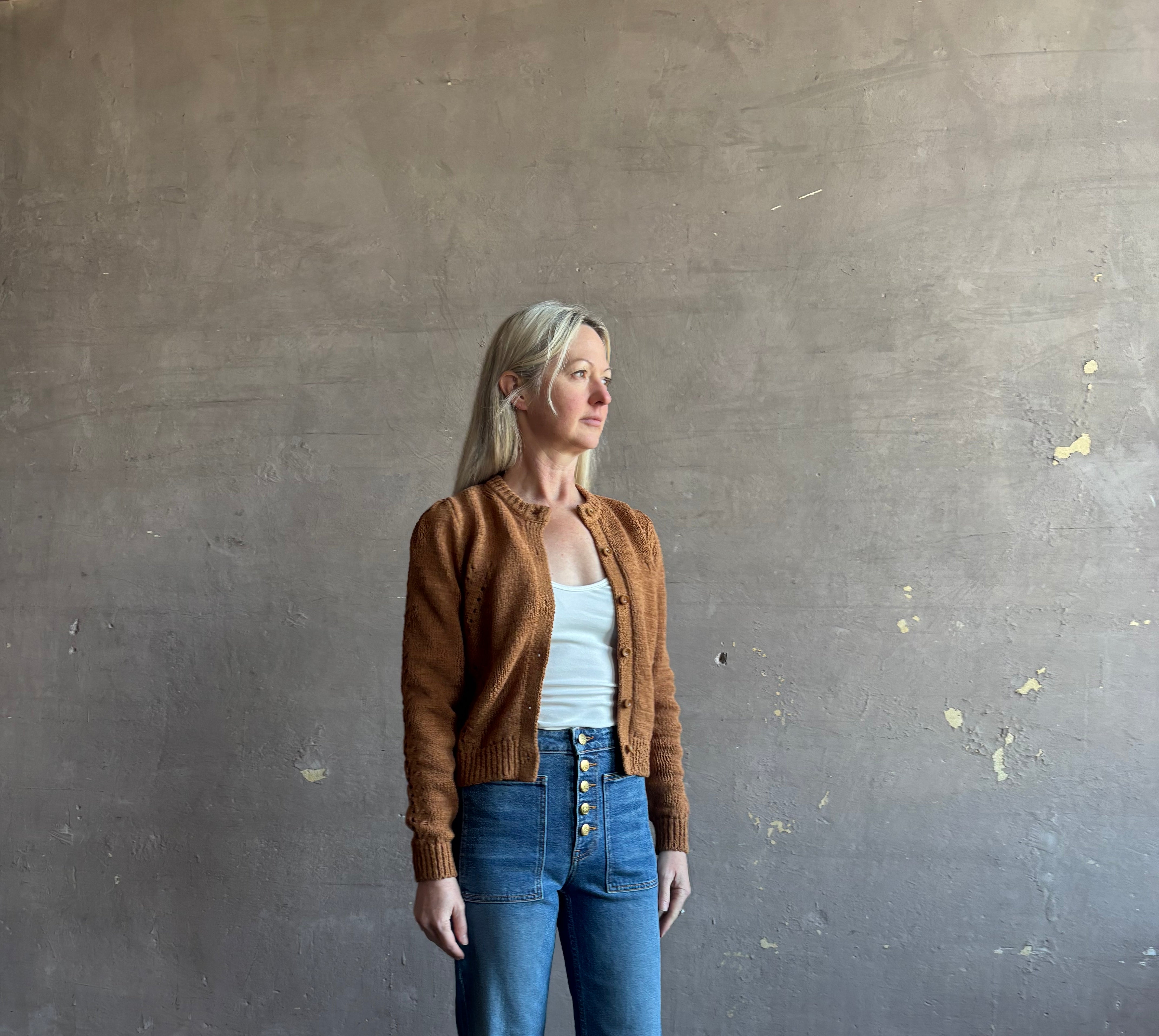 Mature woman wearing the Delphina Long Sleeve women's designer Cardigan from Ulla Johnson rendered in an umber hue with a crew neck and button front