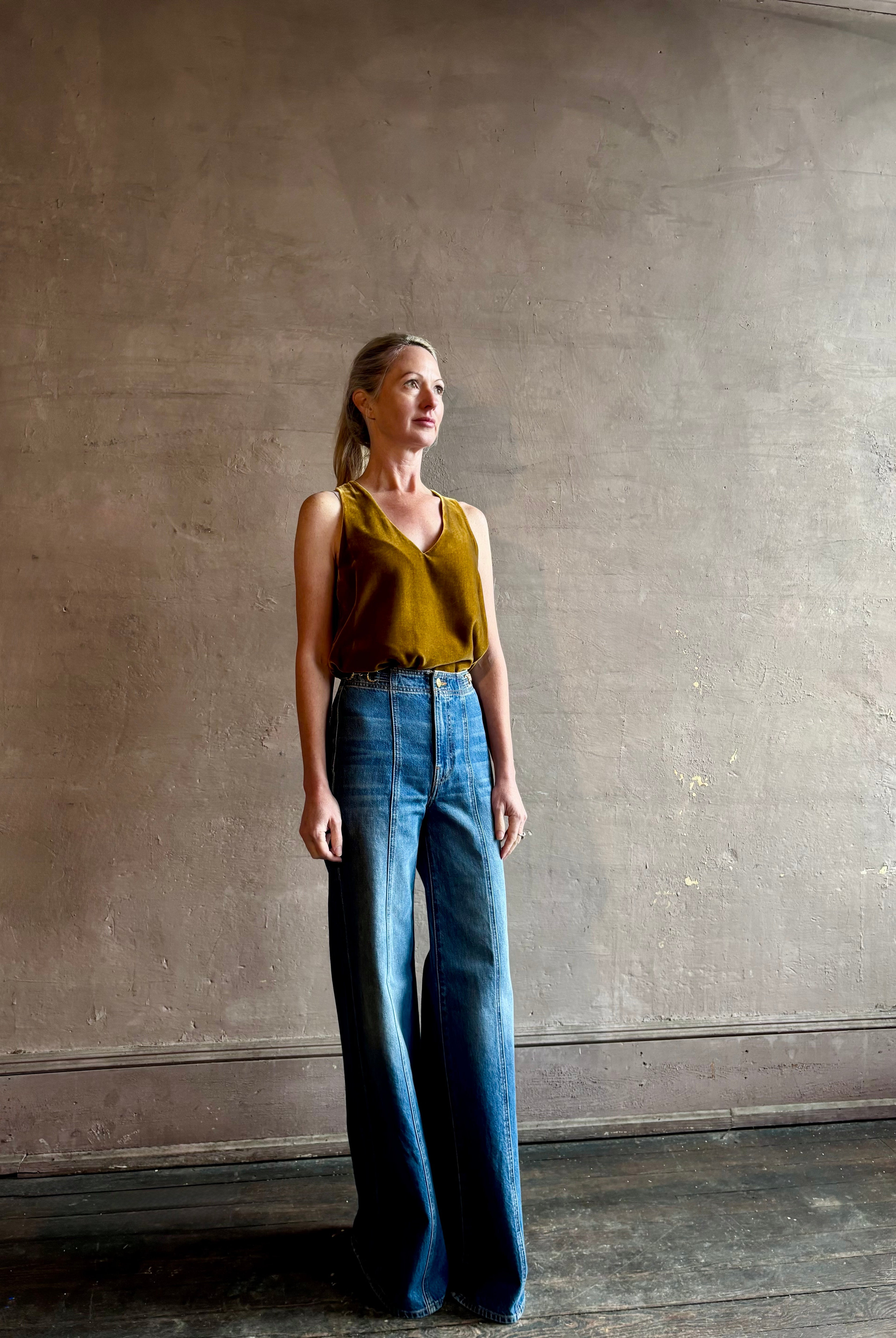 Mature woman wearing designer Ulla Johnson delphine wide leg high rise cotton rigid denim with gold buckle detail zip closure