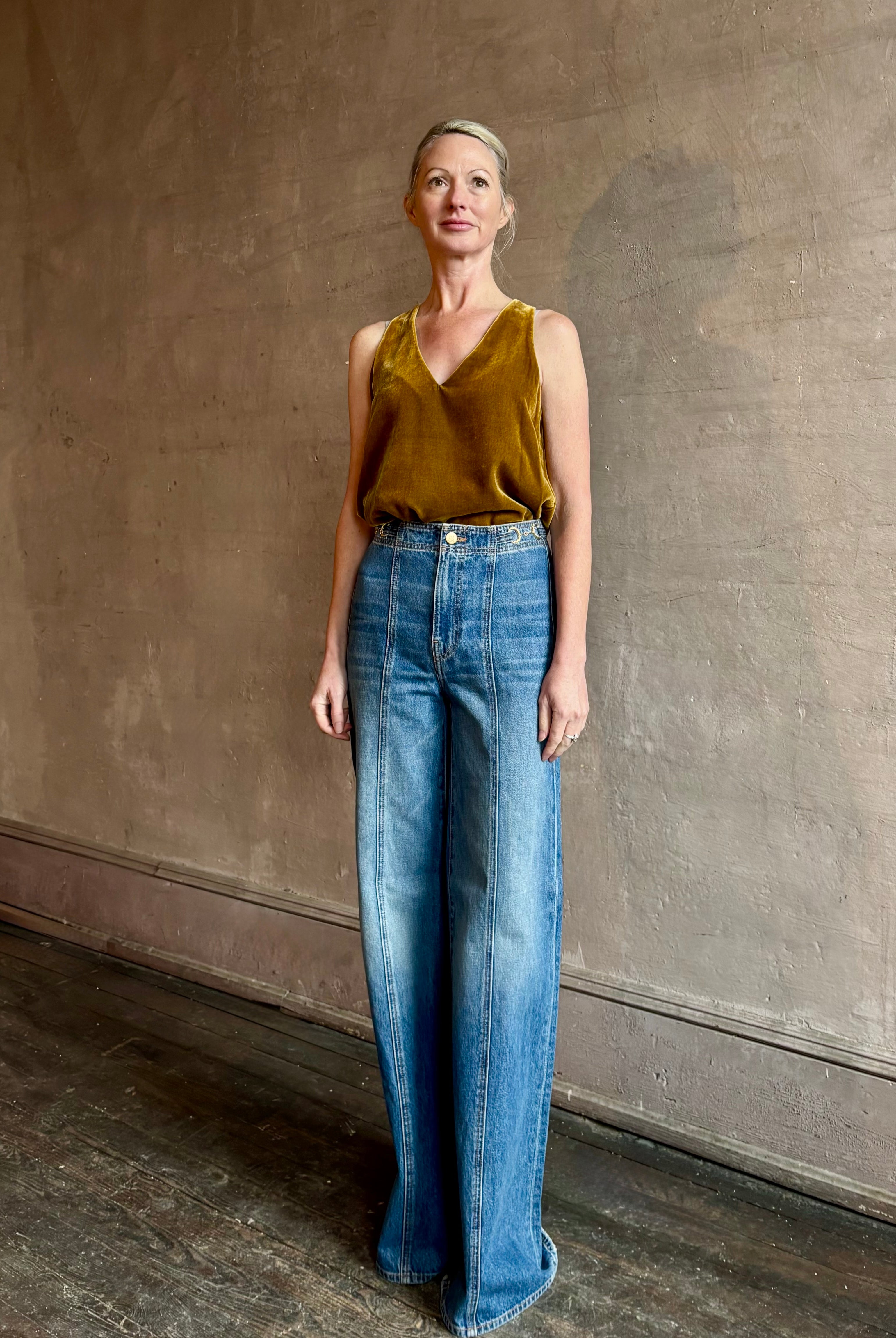 Mature woman wearing designer Ulla Johnson delphine wide leg high rise cotton rigid denim with gold buckle detail zip closure