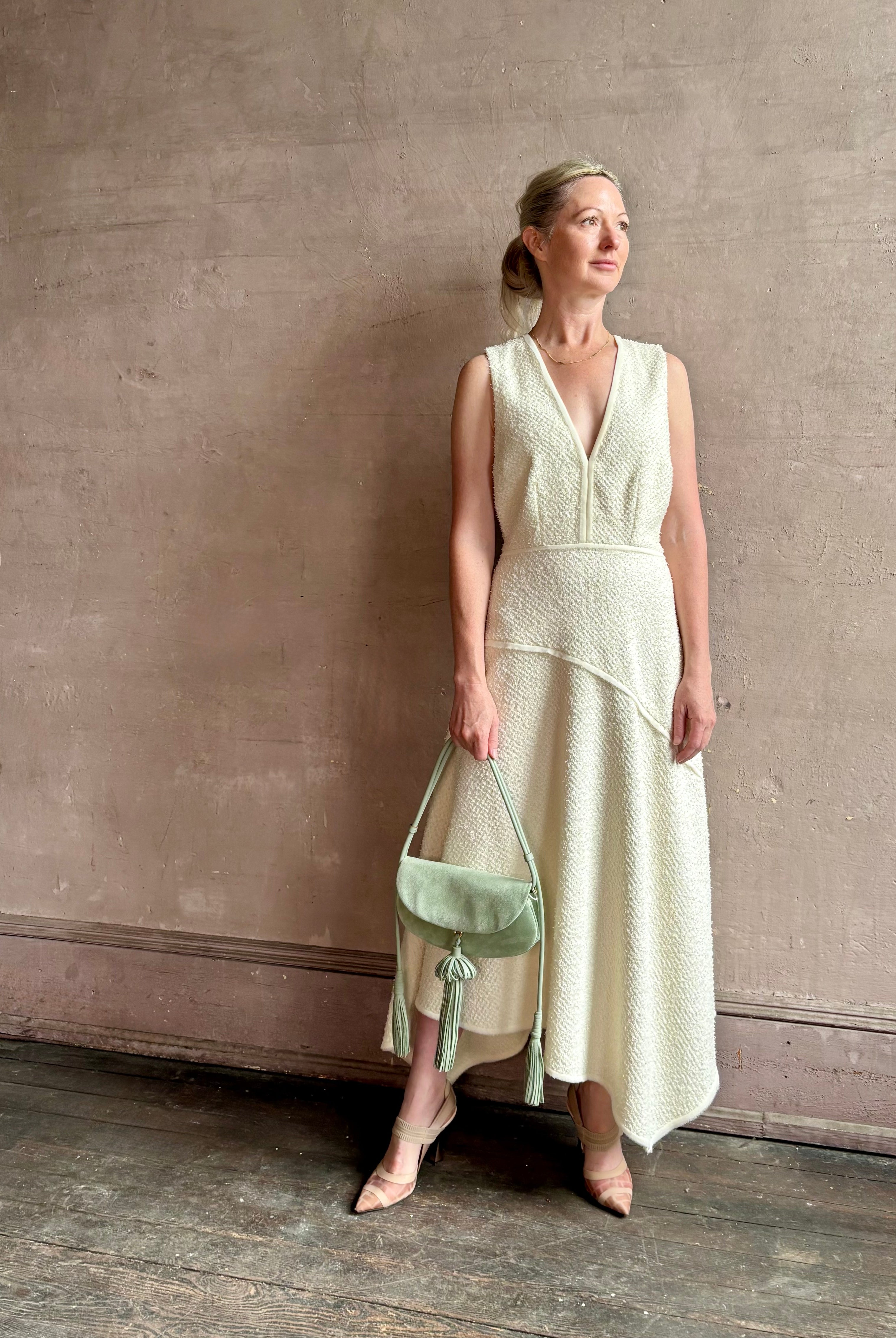Woman wearing Ulla Johnson Florence Dress in textured off-white cotton blend with a v-neckline asymmetrical hem