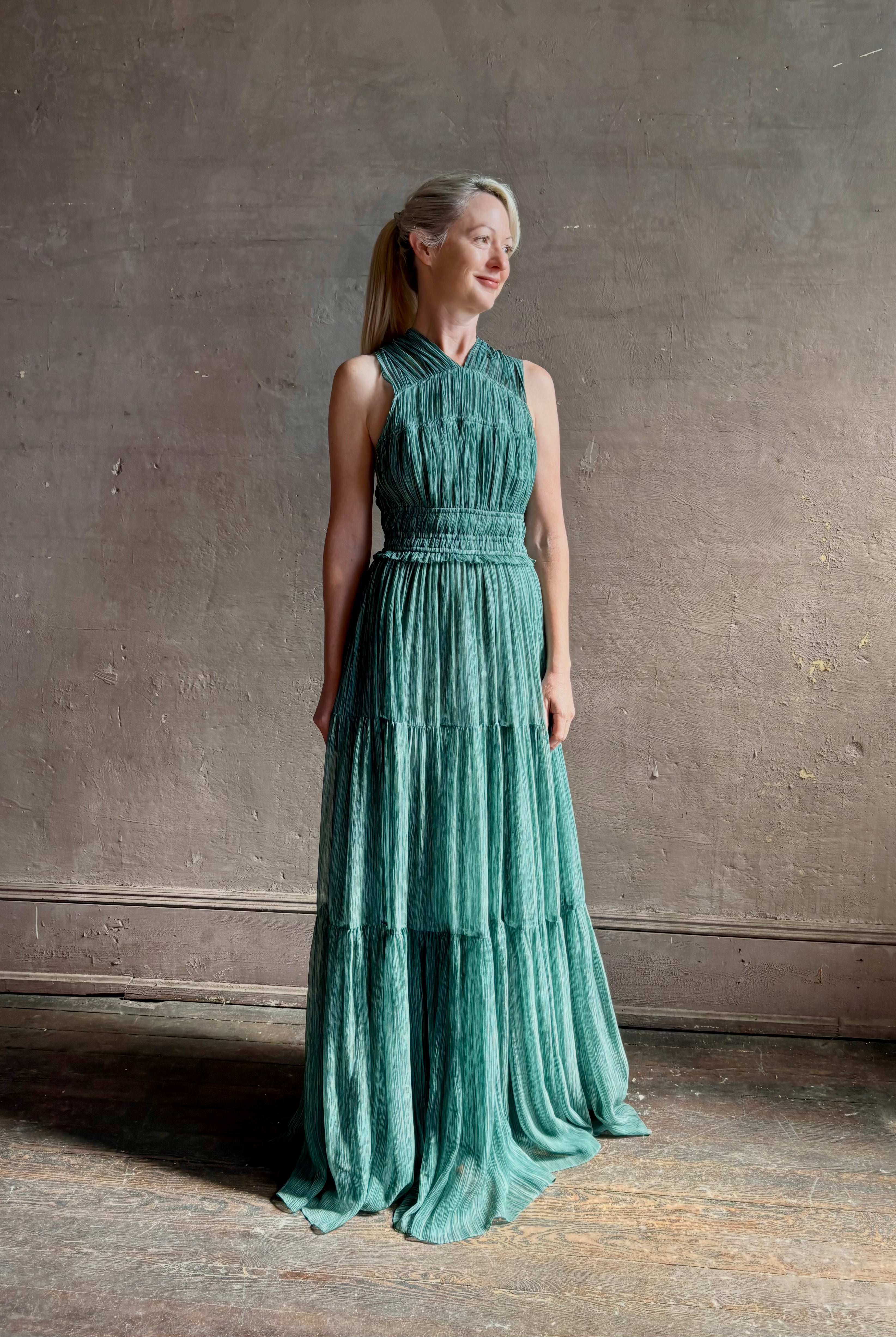 Woman wearing Freesia Gown from Ulla Johnson rendered in a soft green and crafted from luxurious silk crinkle chiffon with low back and flexible waistband