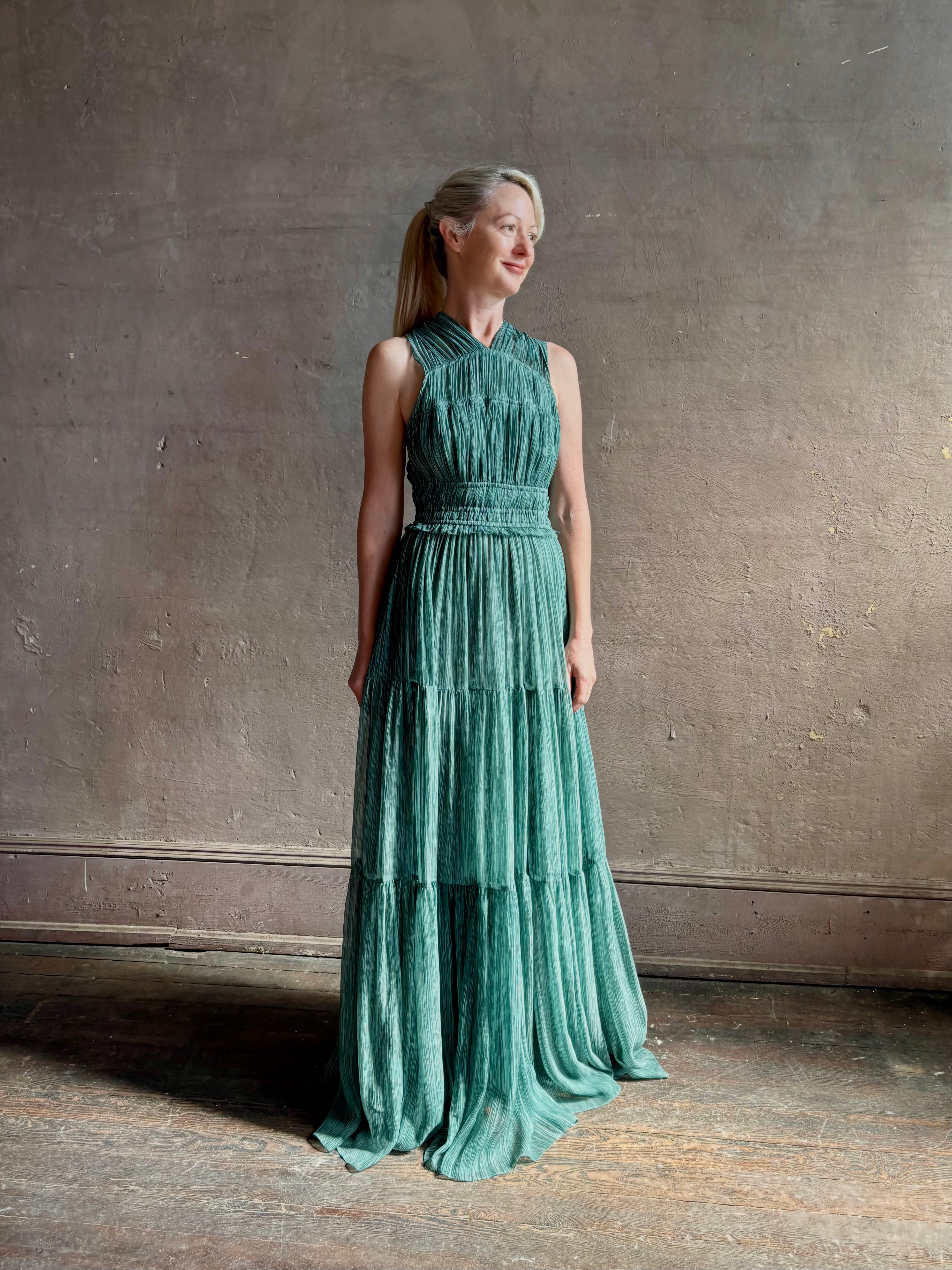 Woman wearing Freesia Gown from Ulla Johnson rendered in a soft green and crafted from luxurious silk crinkle chiffon with low back and flexible waistband