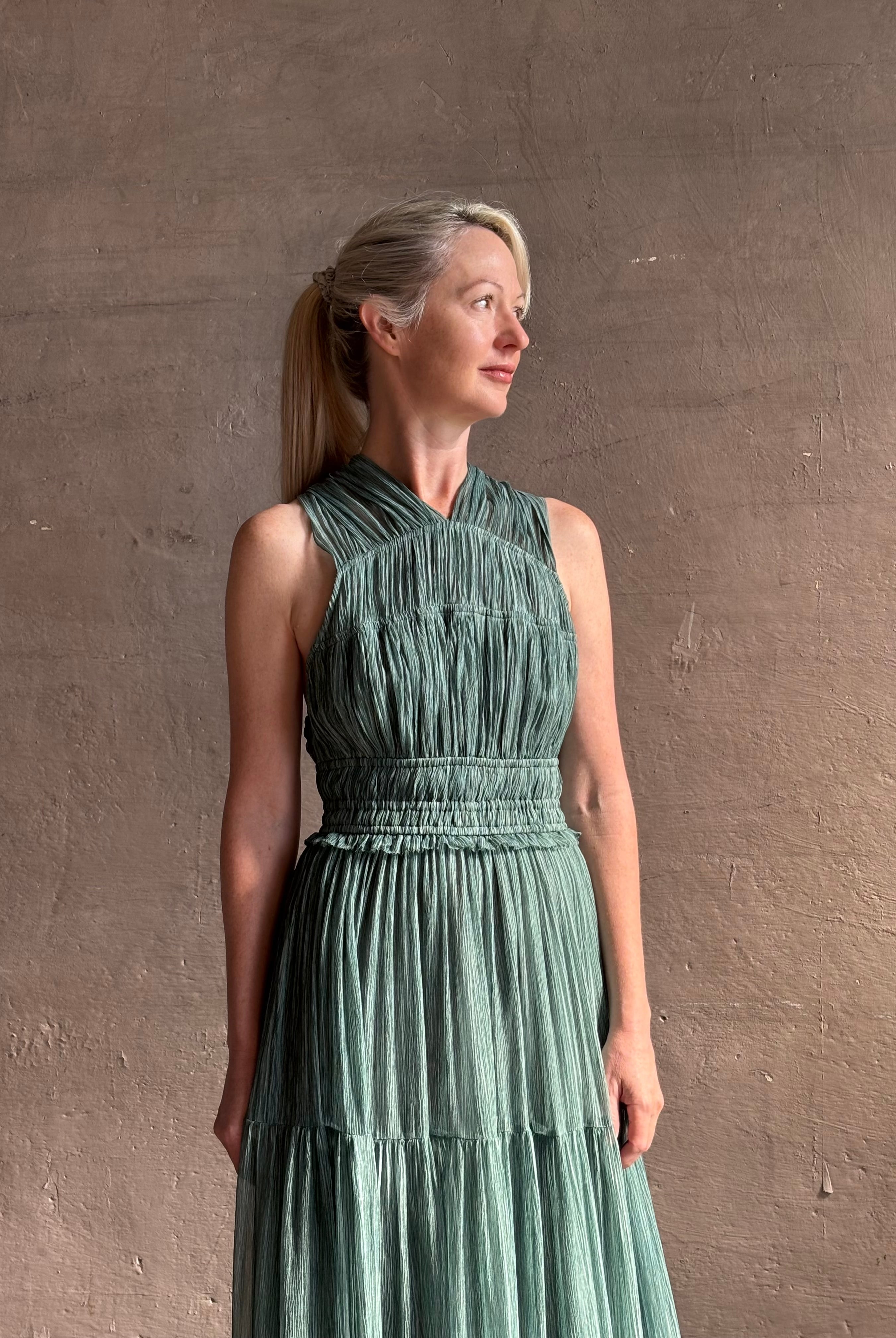 Woman wearing Freesia Gown from Ulla Johnson rendered in a soft green and crafted from luxurious silk crinkle chiffon with low back and flexible waistband