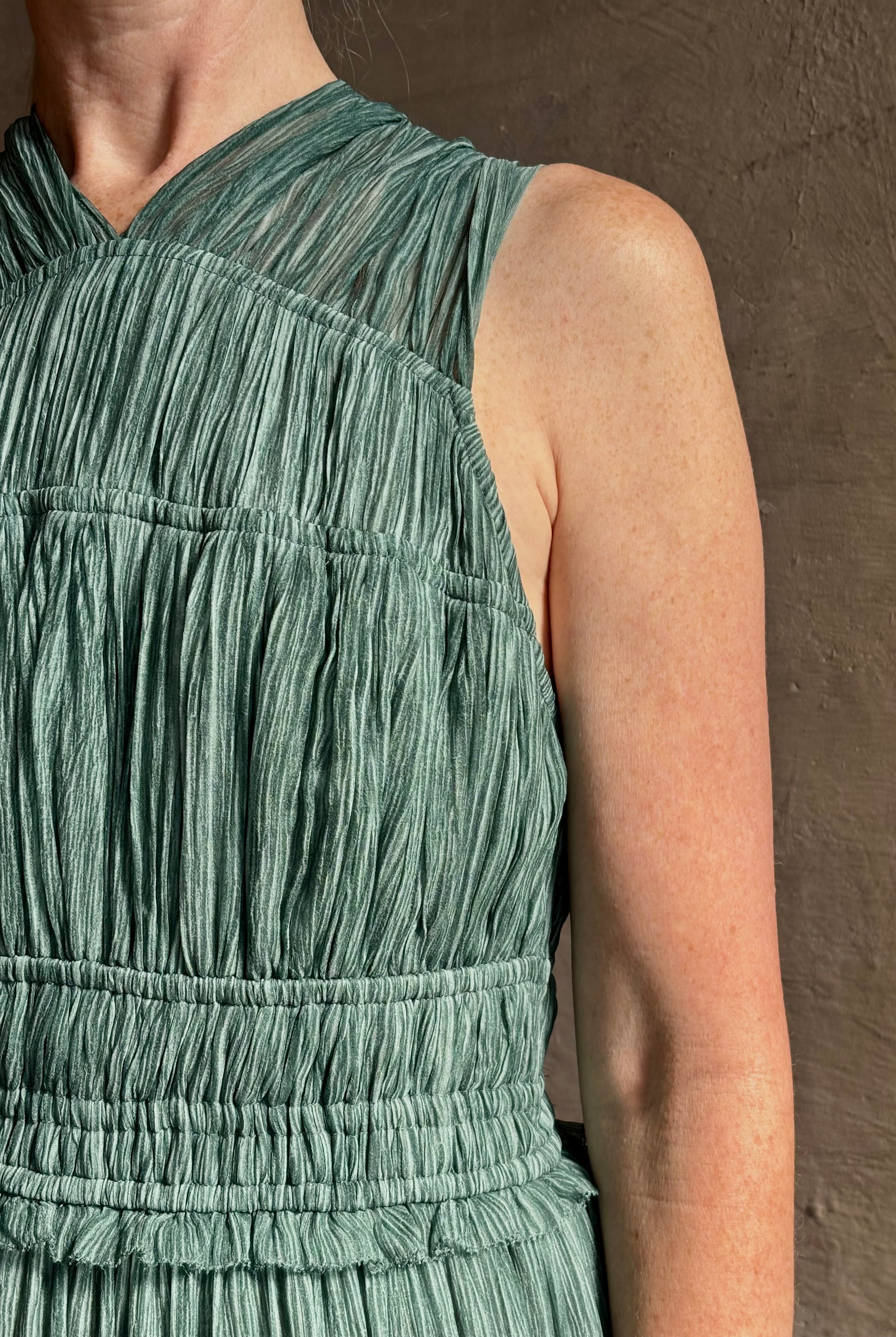 Woman wearing Freesia Gown from Ulla Johnson rendered in a soft green and crafted from luxurious silk crinkle chiffon with low back and flexible waistband