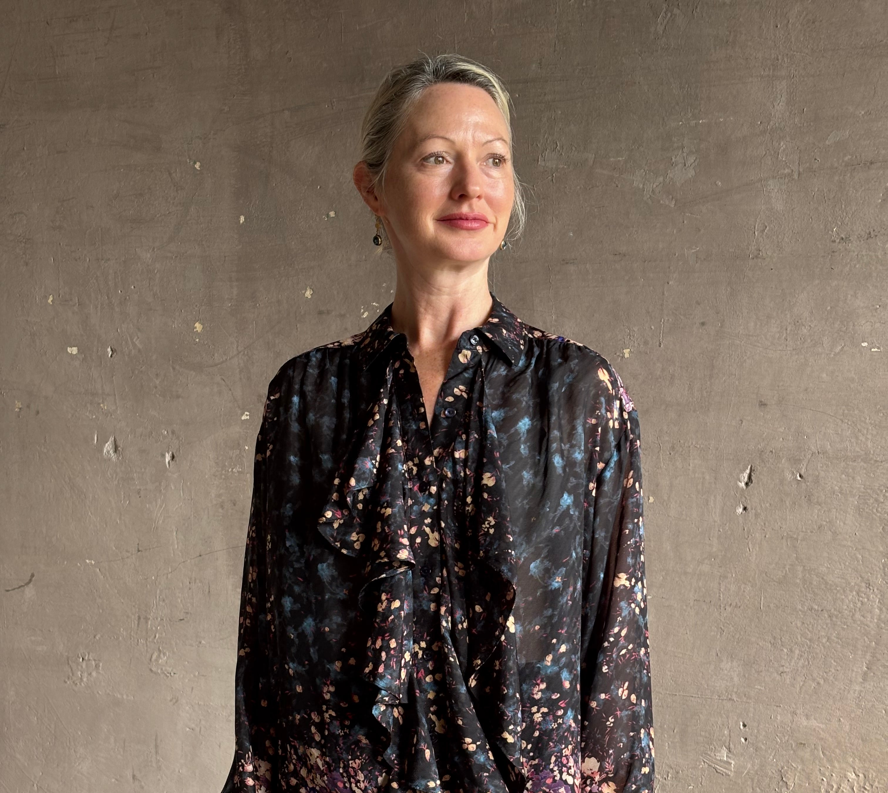 woman wearing designer Ulla Johnson long-sleeve black silk blouse subtle floral print collared button front ruffle
