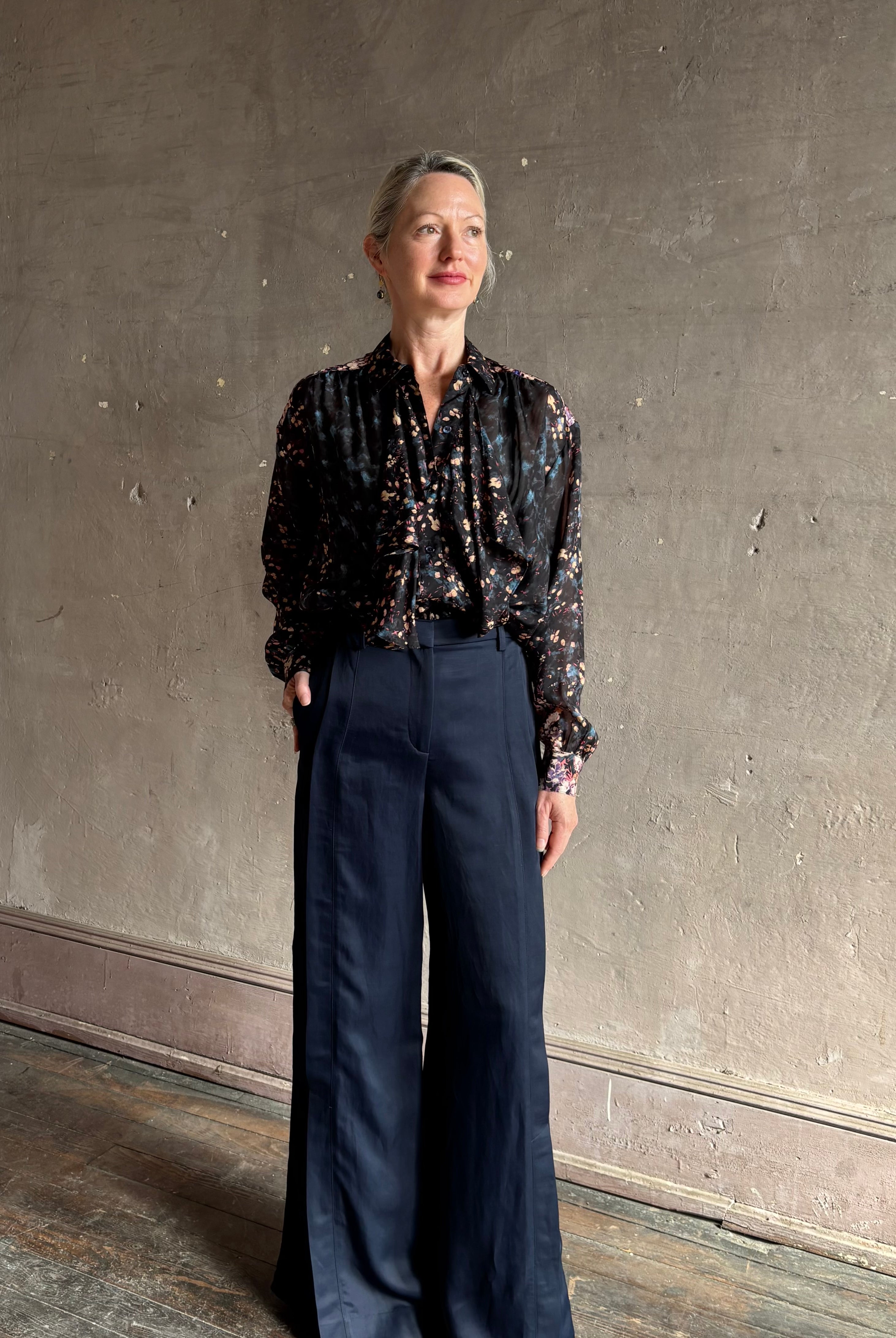 woman wearing Ulla Johnson long-sleeve black silk blouse subtle floral print collared button front ruffle detail