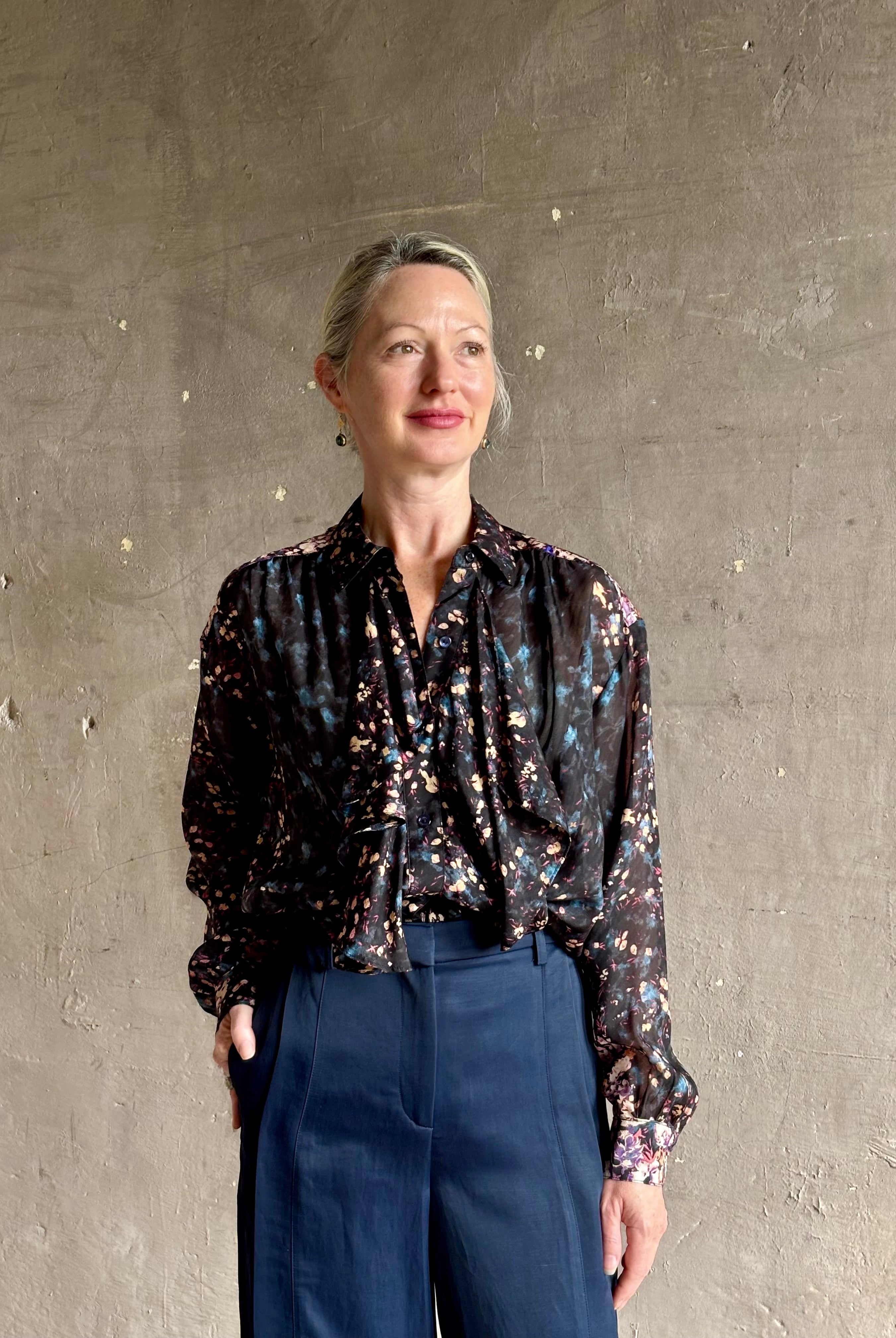 woman wearing designer Ulla Johnson long-sleeve black silk blouse subtle floral print collared button front ruffle