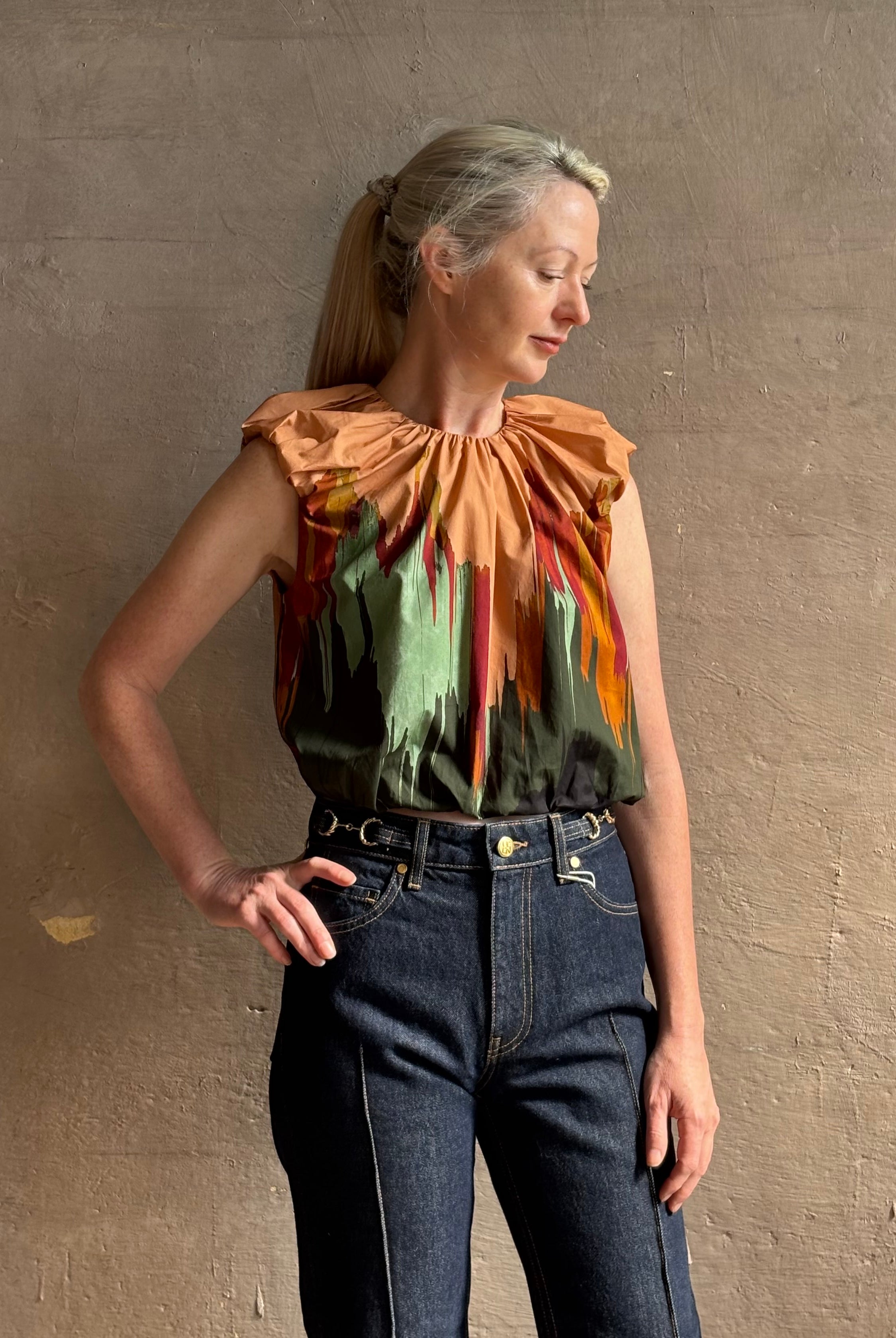 Mature woman wearing Women's designer Gracie sleeveless Cotton Top from Ulla Johnson rendered in a rich abstract Agate print composed of dark green, mint green, burgundy, terra cotta, and sienna and crafted from lightweight cotton poplin
