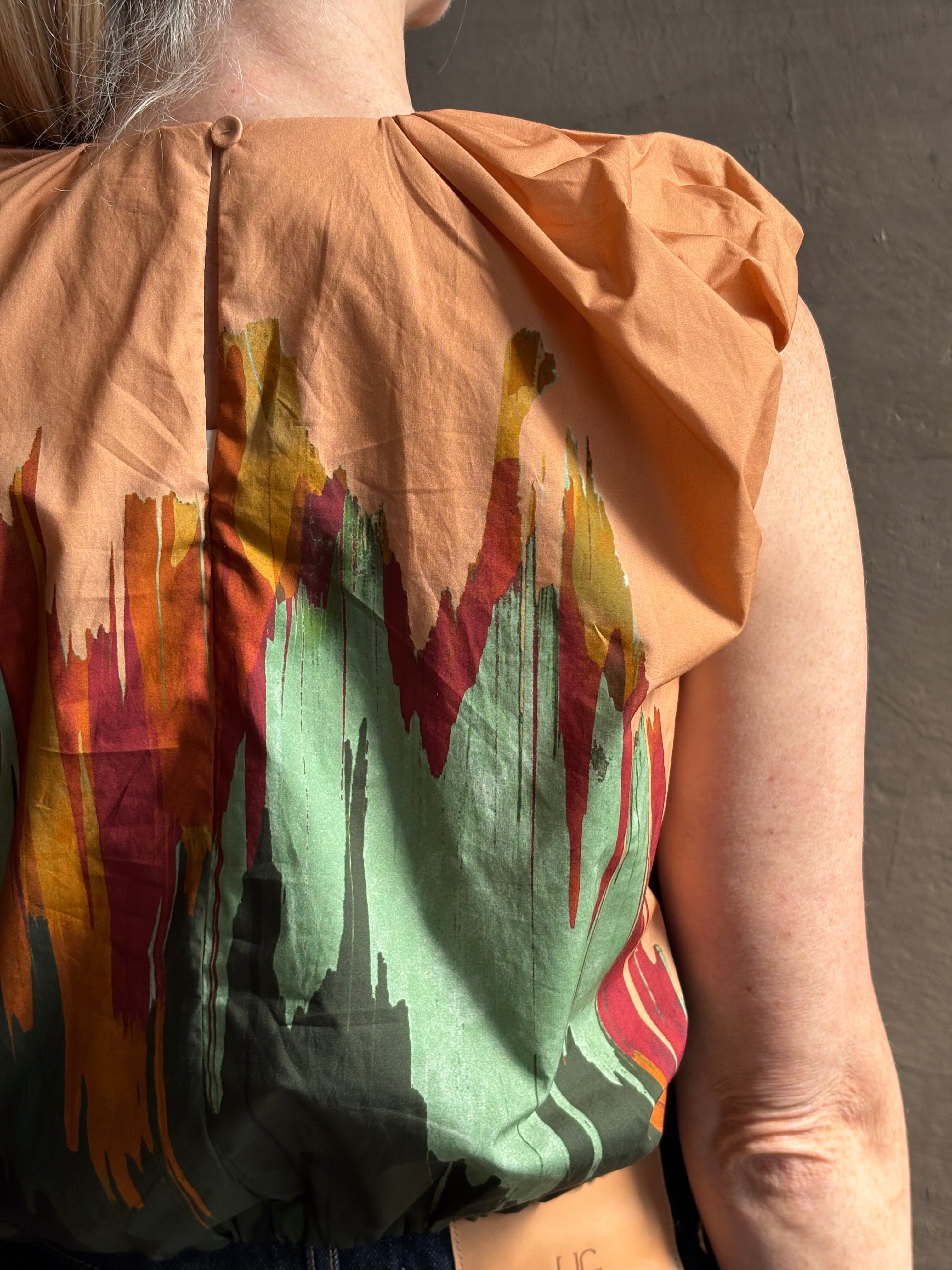 Mature woman wearing Women's designer Gracie sleeveless Cotton Top from Ulla Johnson rendered in a rich abstract Agate print composed of dark green, mint green, burgundy, terra cotta, and sienna and crafted from lightweight cotton poplin