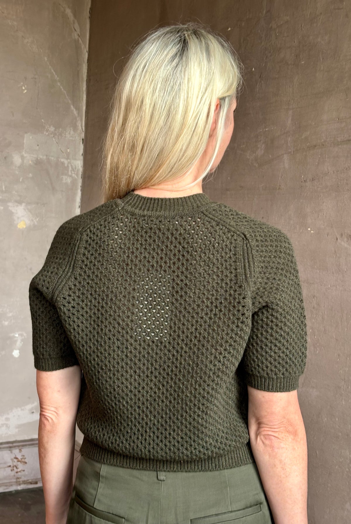 Mature woman wearing designer Ulla Johnson Imara Short Sleeve dark green Sweater with a dimensional open weave